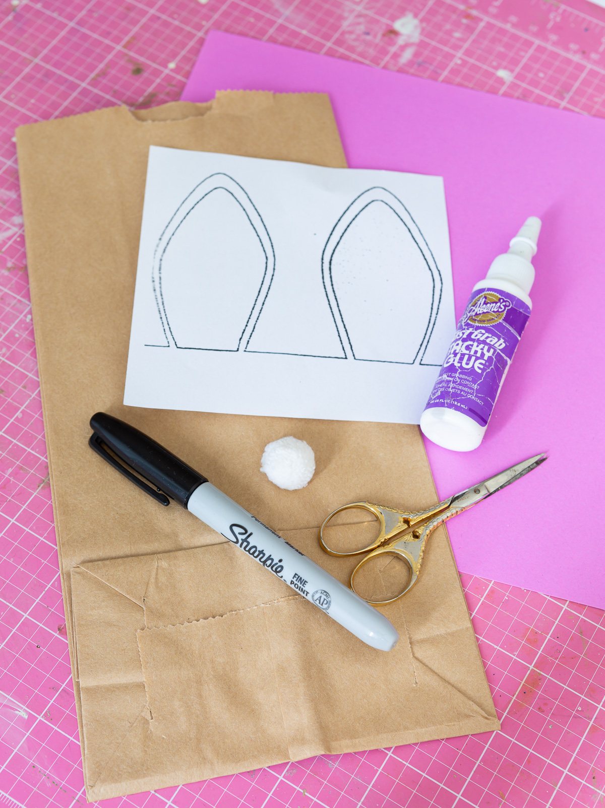 supplies and bunny ear template needed to make an Easter bunny bag using a brown paper bag.
