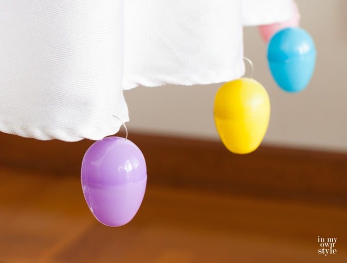 Easter eggs hanging on the edge of a white tablecloth