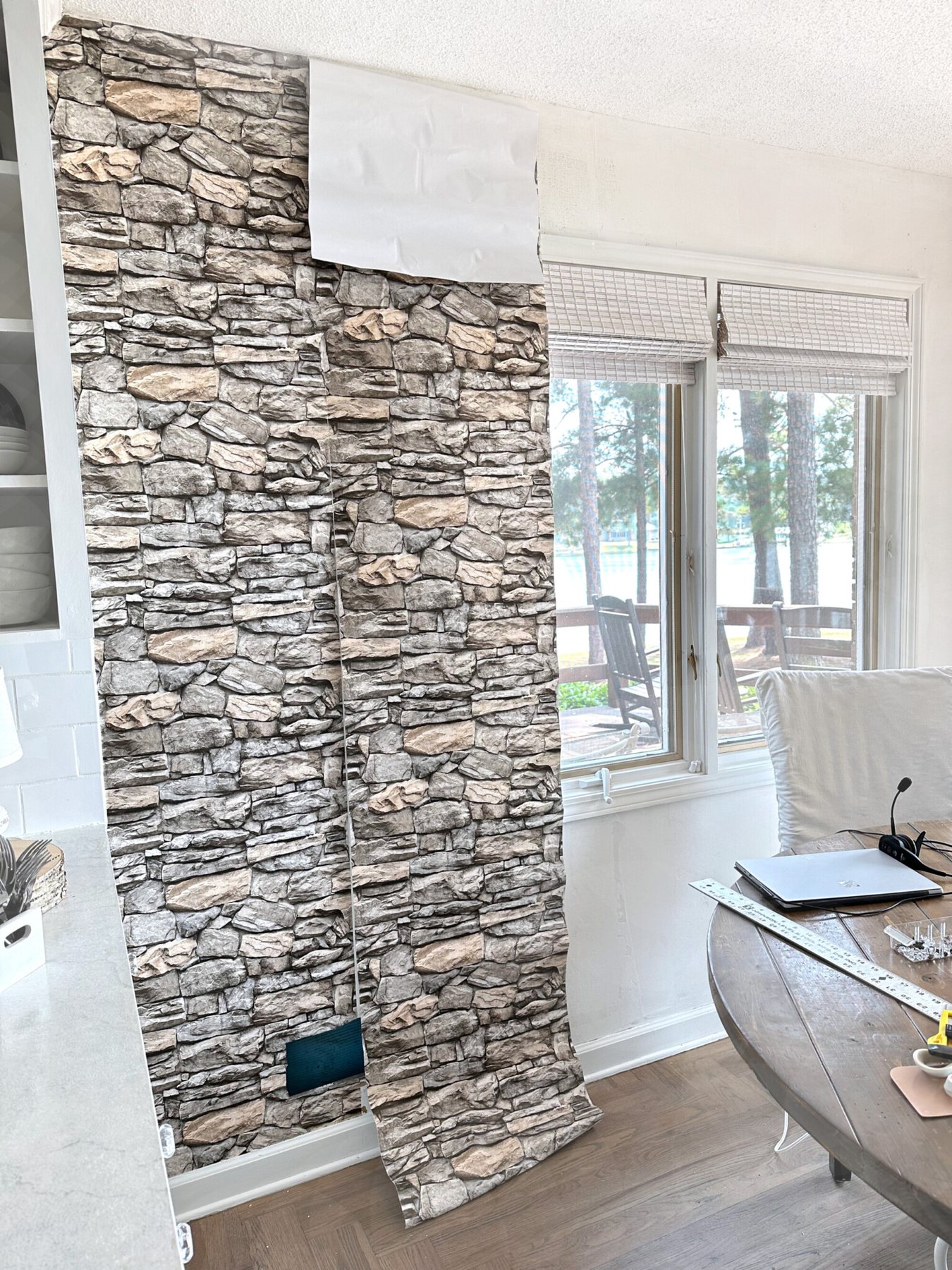 putting peel and stick wallpaper in a stacked stone pattern on a wall in a kitchen.