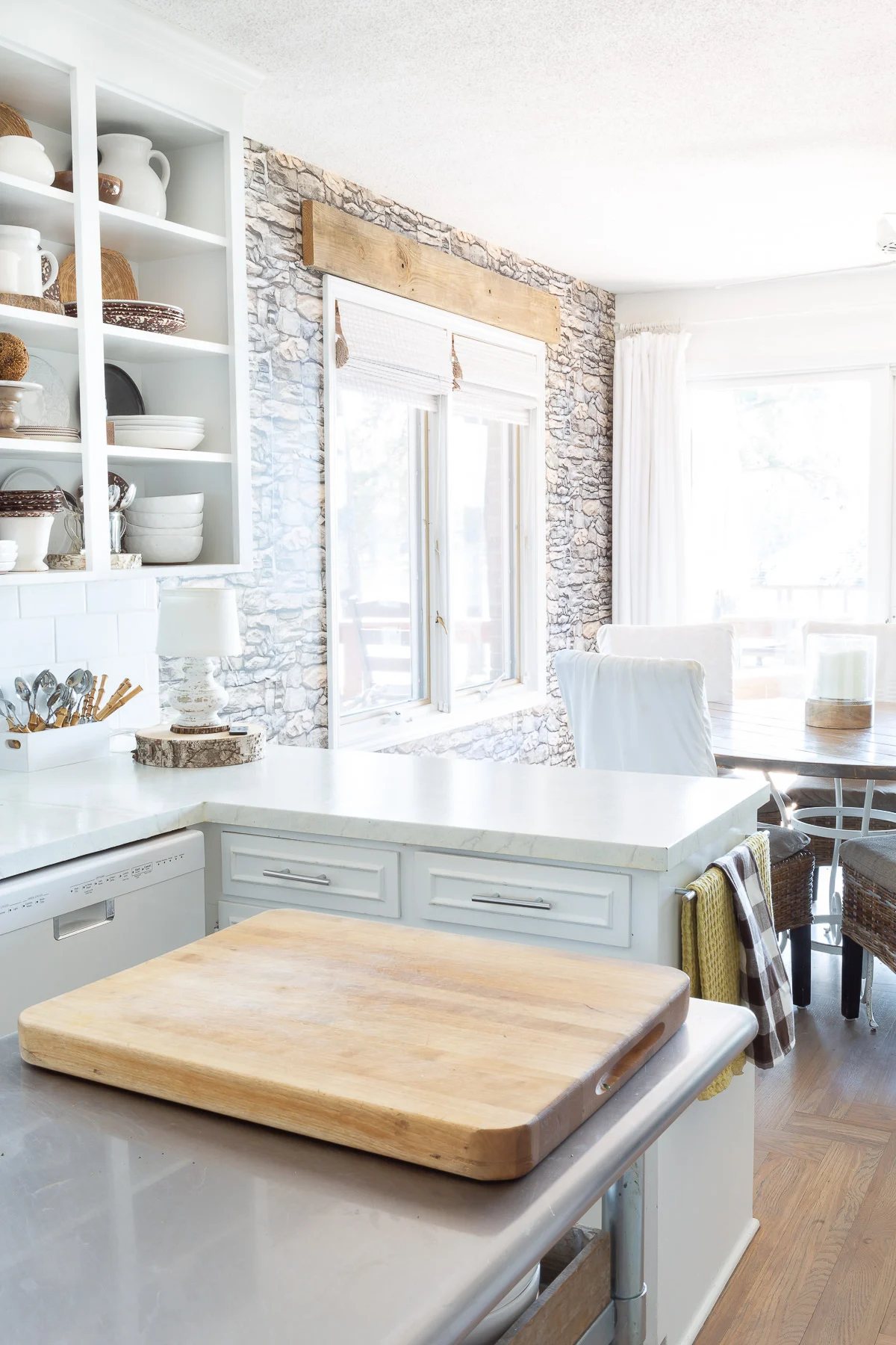 Peel and stick stacked stone wallpaper on a accent wall in a white kitchen.