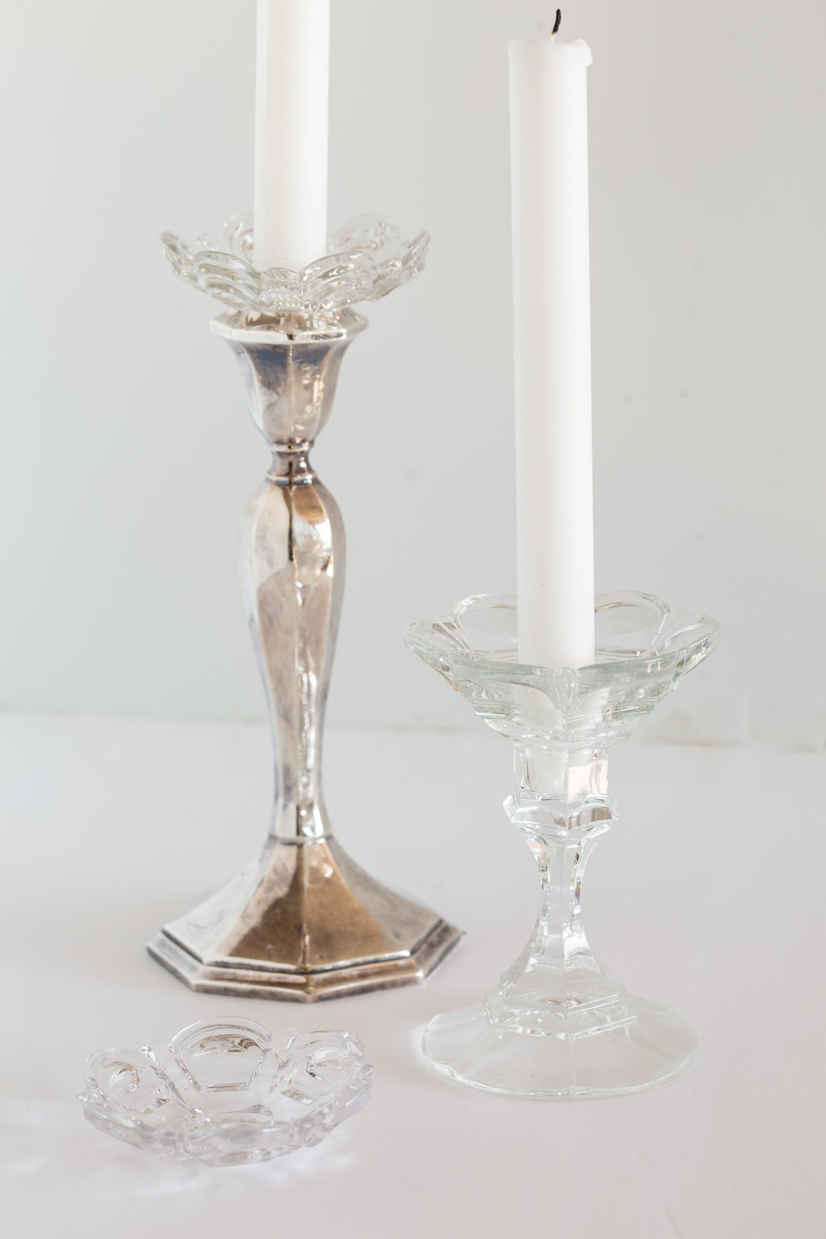 Two candlestick holders with glass bobeches or candle rings on them to catch candle drips.
