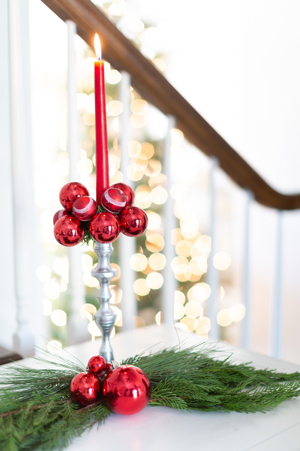 Red candle in a silver candle holder with red ball ornaments made into a Christmas candle ring.
