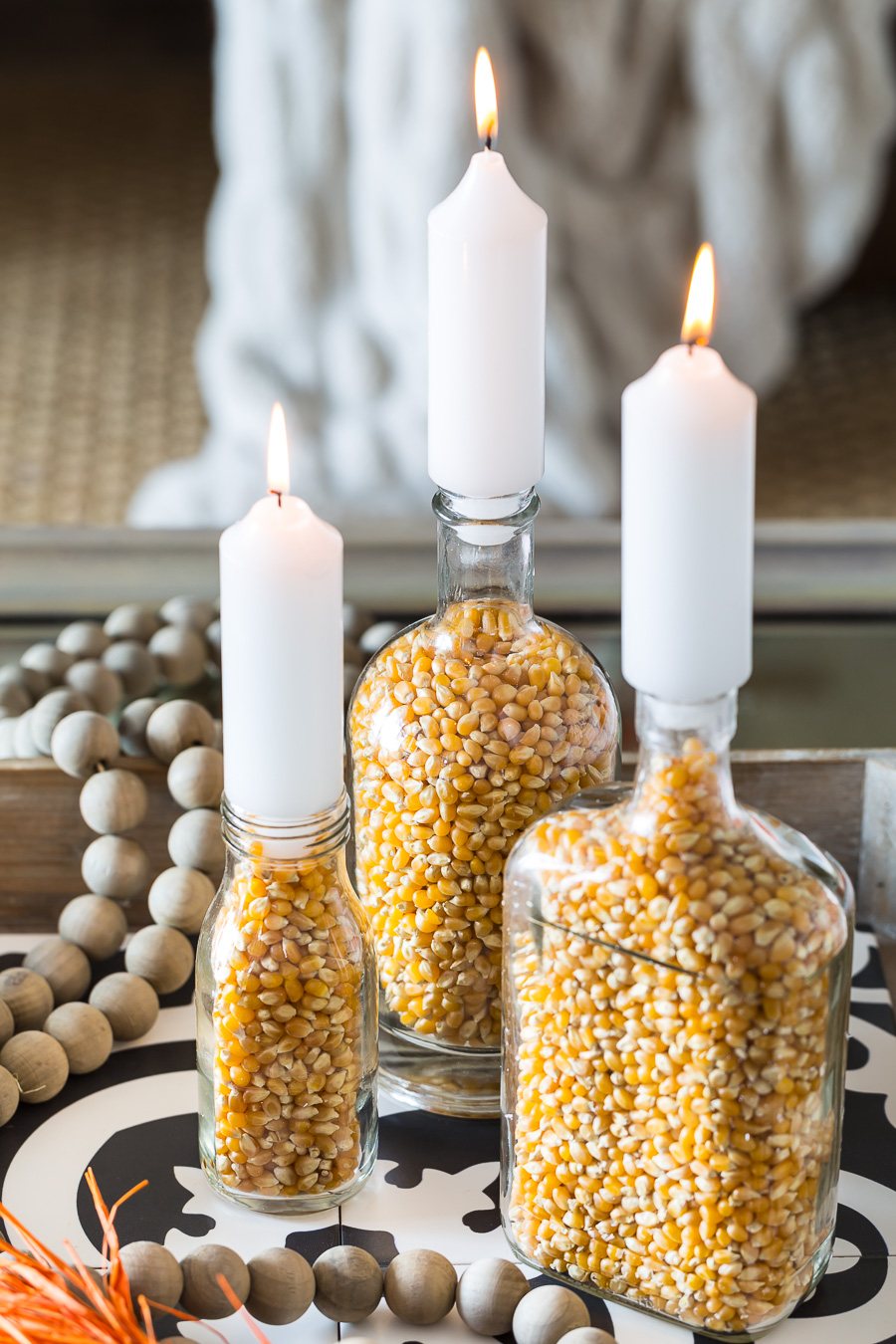 Close up of 3 popcorn filled glass bottle fall candle holders.