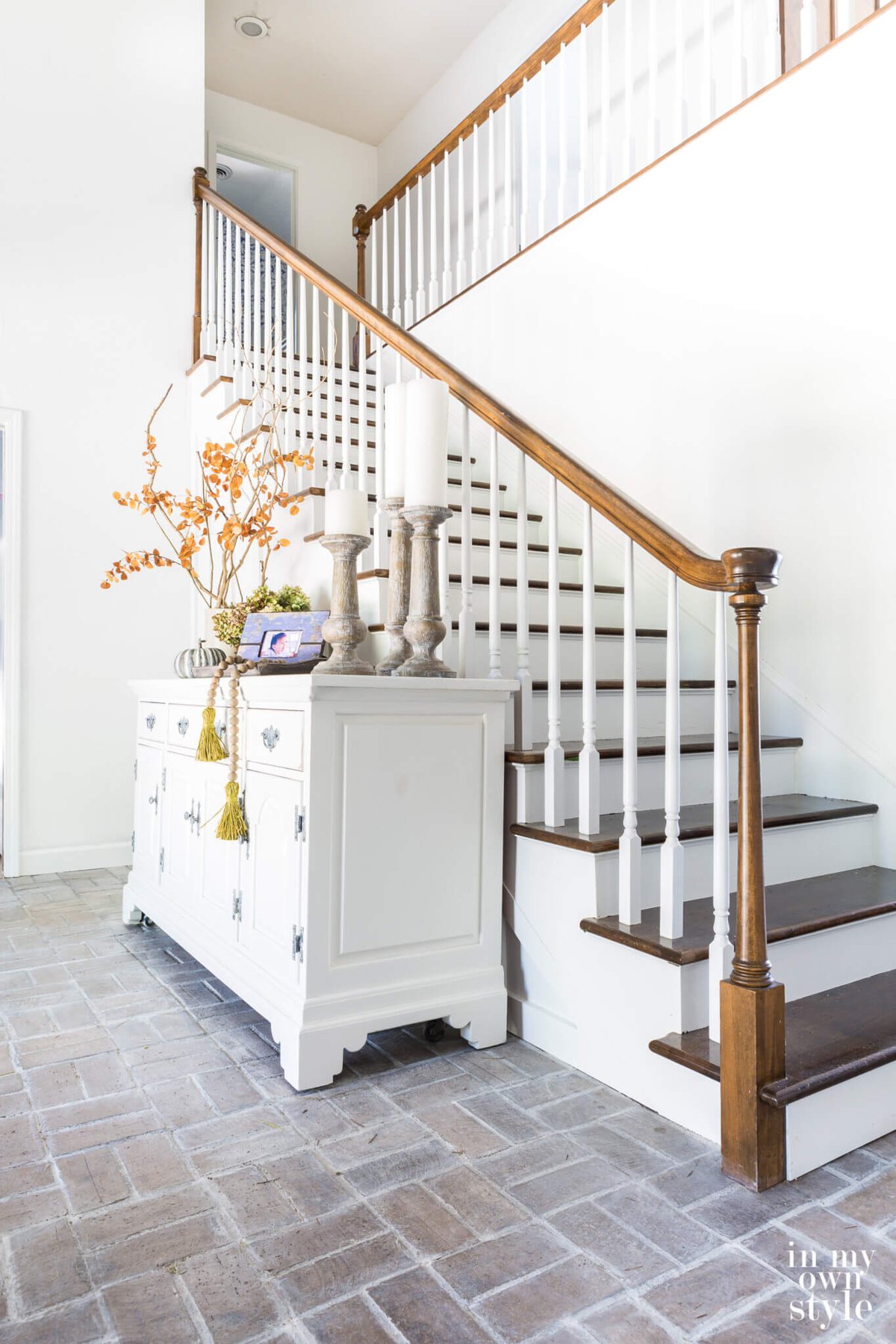 White sideboard decorated for fall in two story entry.