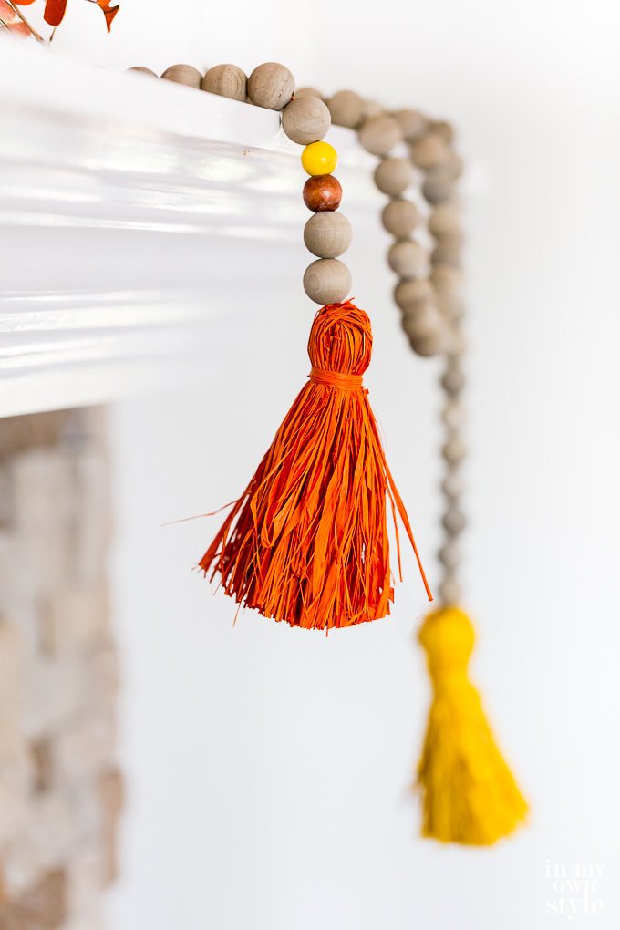 Driftwood stained wood bead garland for Fall with colorful raffia tassels.