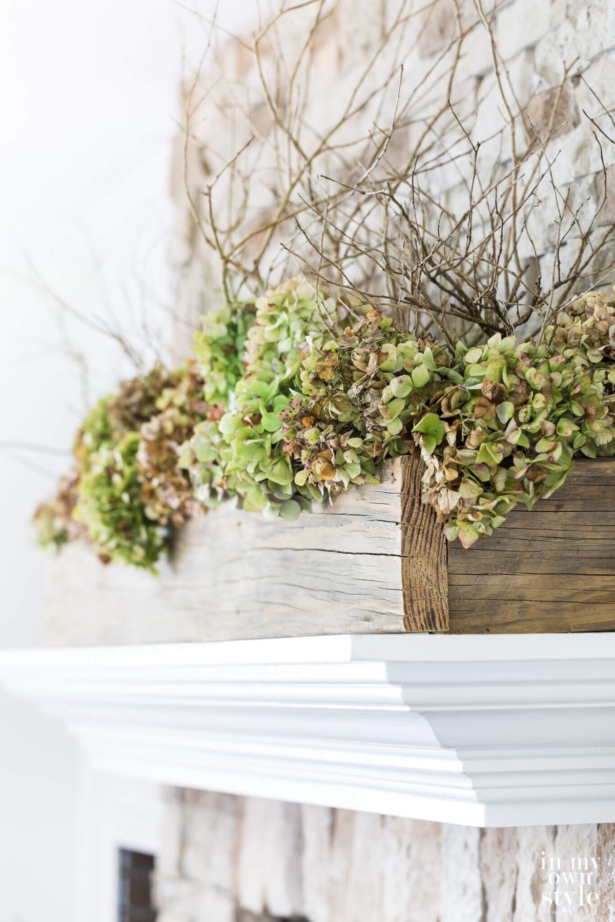 Long reclaimed wood planter with dried hydrangeas on white mantel.