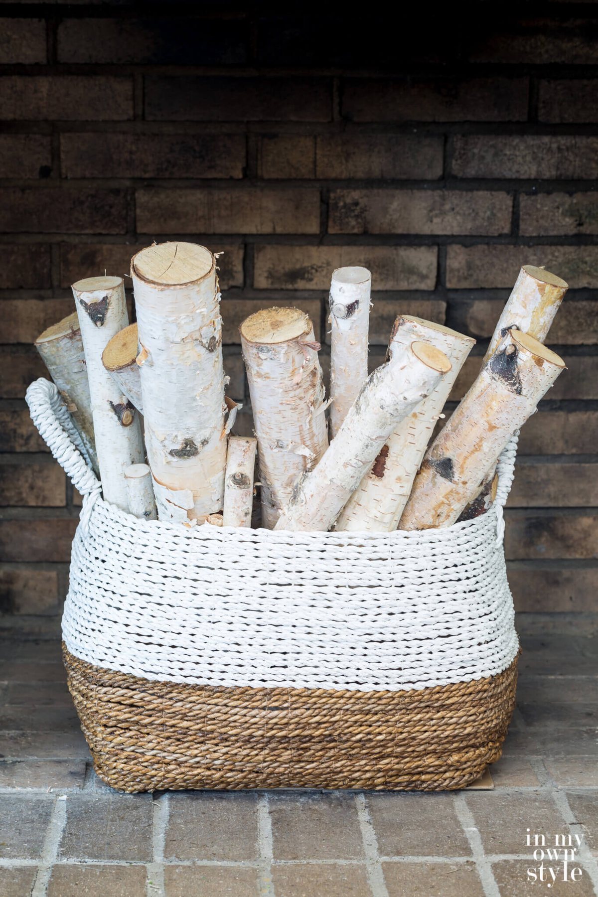 Bundle of Birch logs in a large basket in a fireplace.