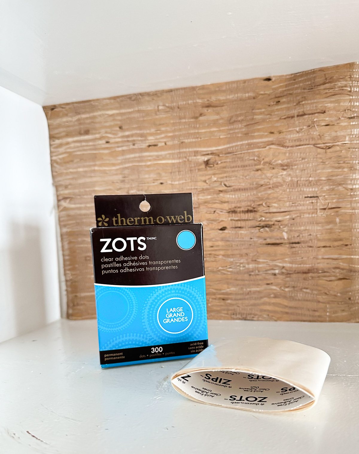 Zots clear adhesive dots ready to be used to attach wallpaper to the back of open kitchen shelves that are getting a color makeover for fall.