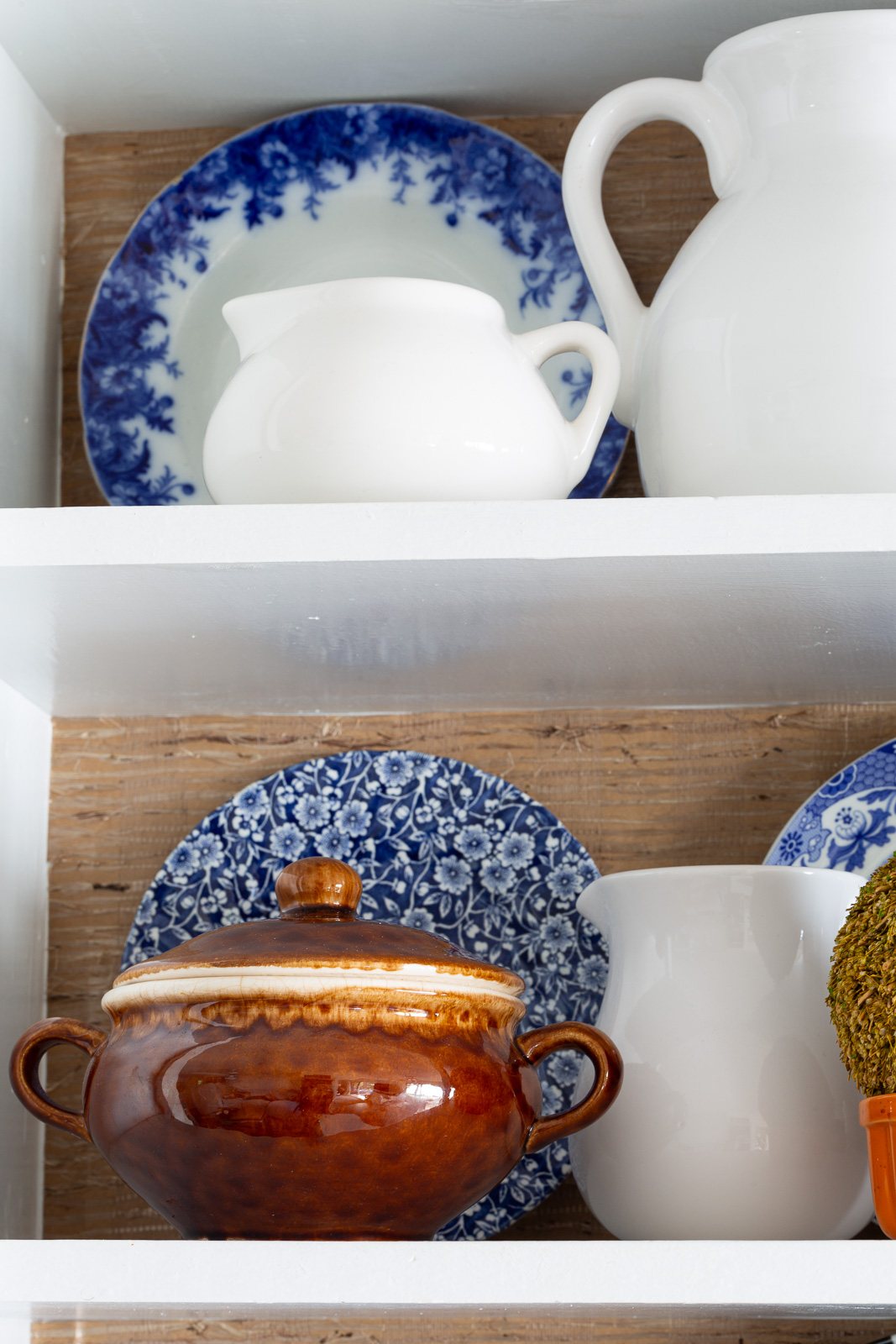 Fall colored kitchen items displayed on open shelves in a small kitchen decorated for fall.