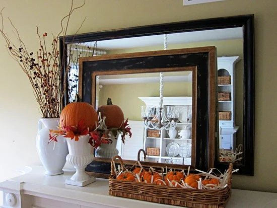 Fall flowers and branches in a white urn on a mantel. decorated for autumn.
