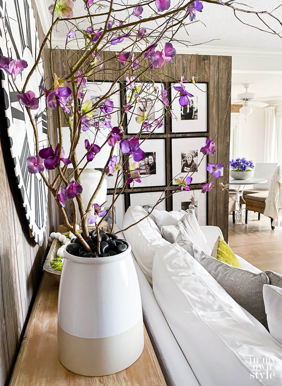 Faux blooming branches in large planter behind a sofa