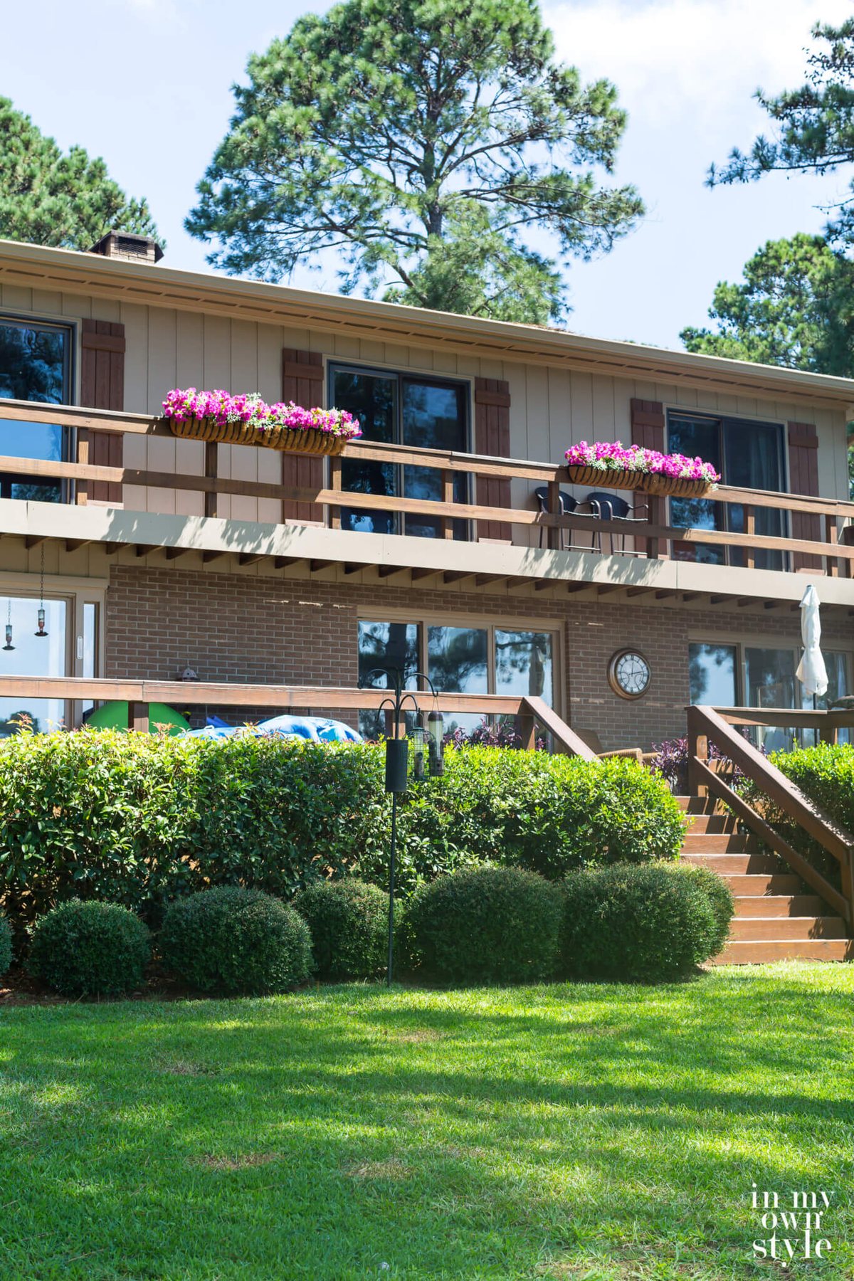 Fake pink flowers in deck railing planters on house.