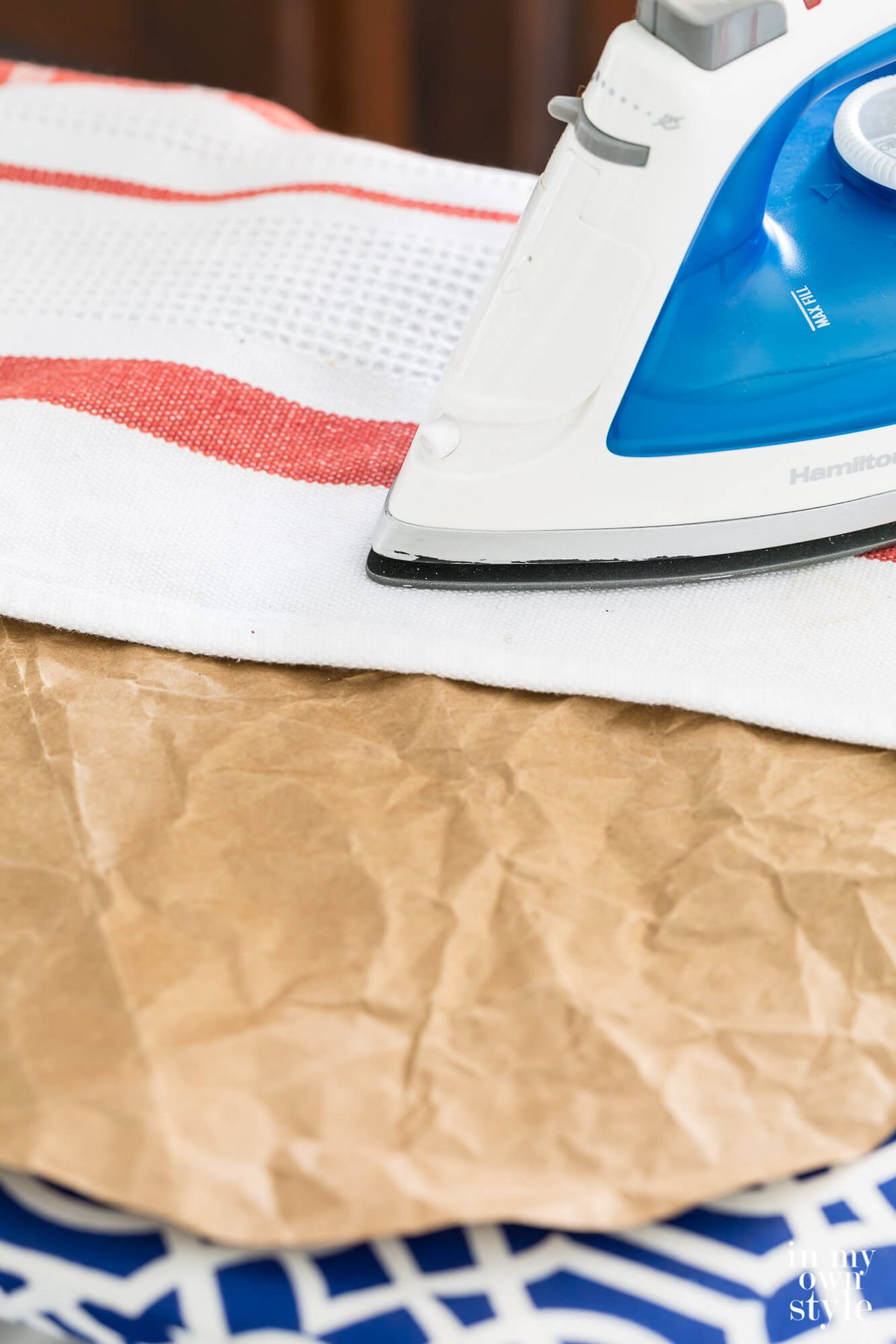 Ironing a brown paper bag using a pressing cloth.