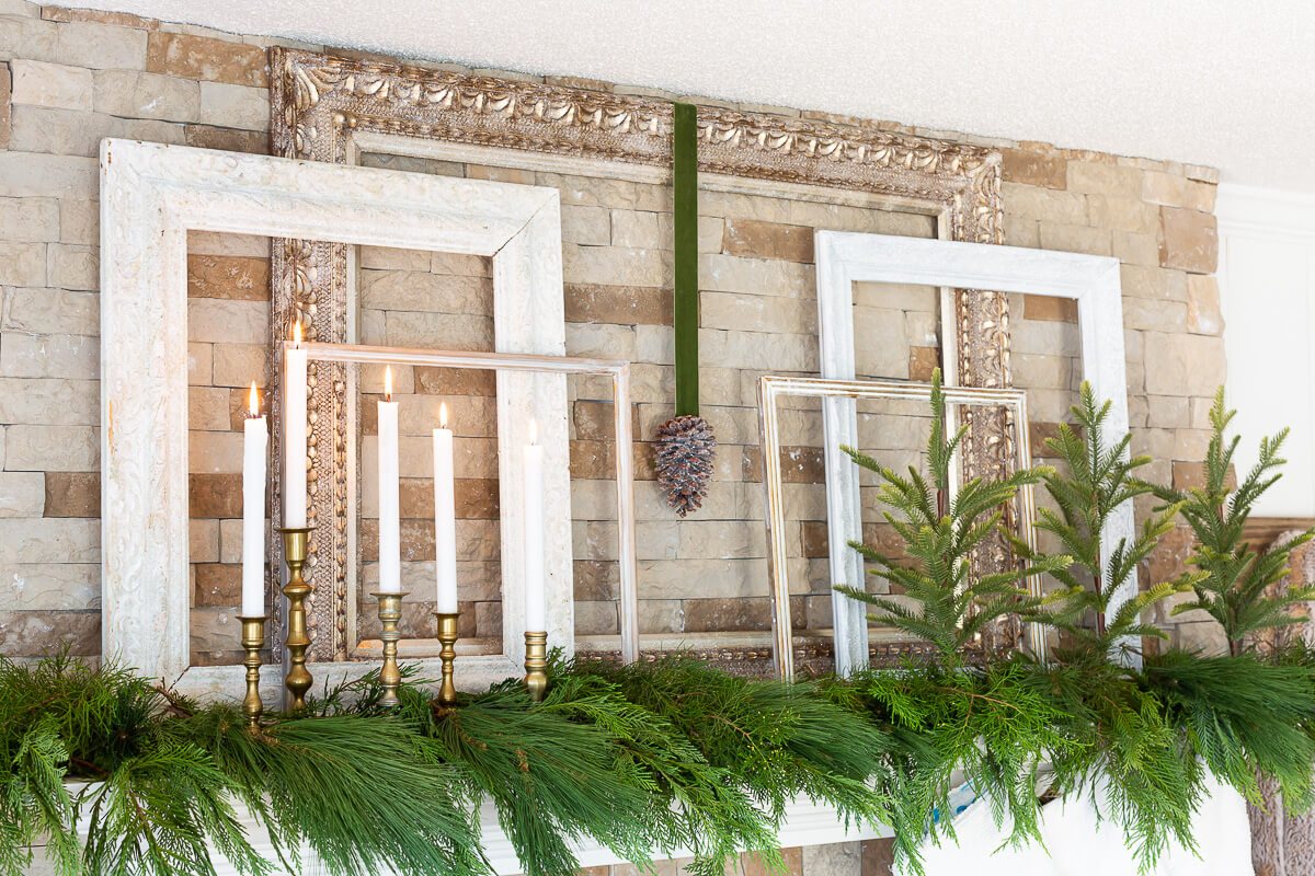 Christmas mantel decorated using 5 frames of various sizes - greenery and candles.