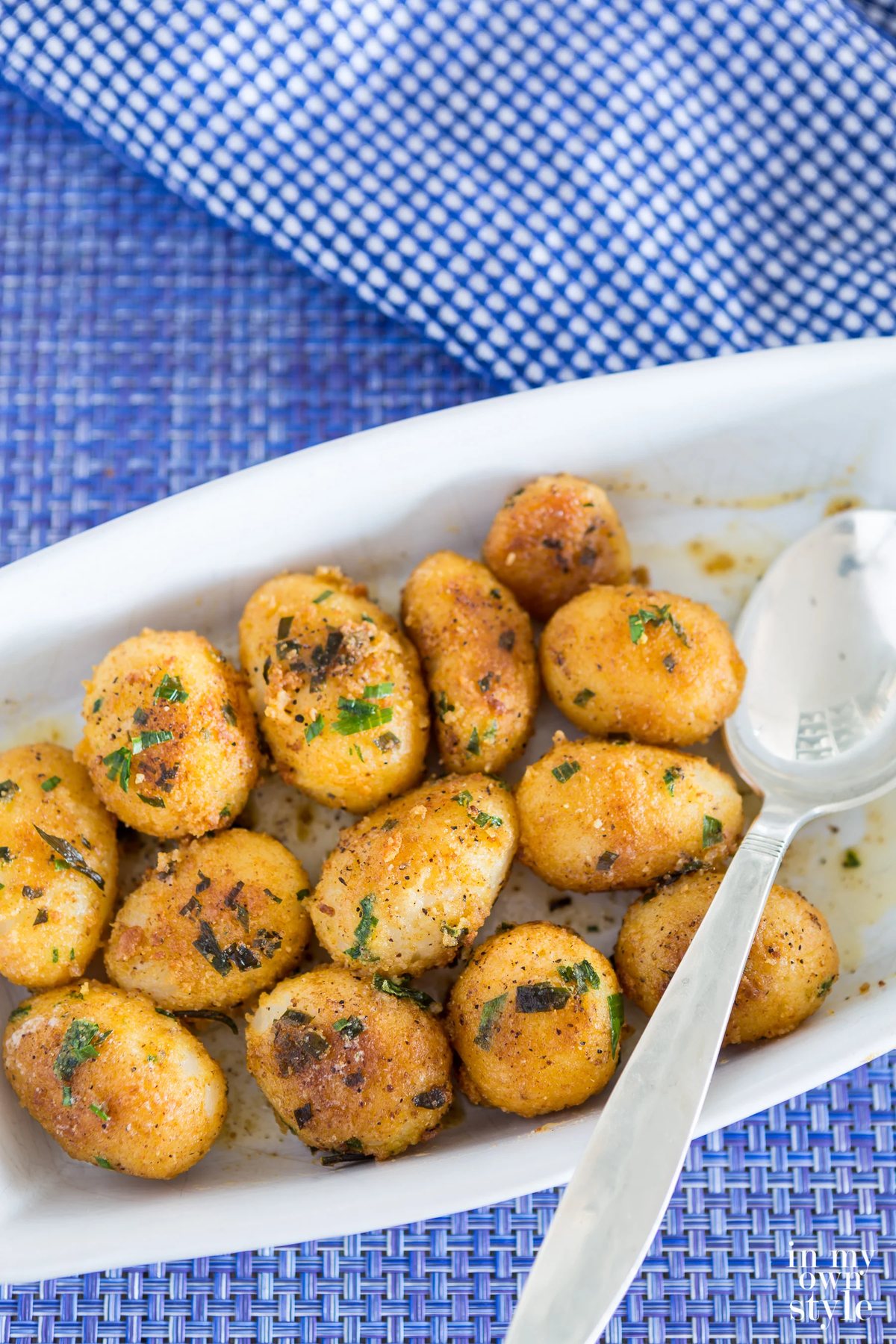 Herbed canned potato recipe served in white dish on blue table cloth.