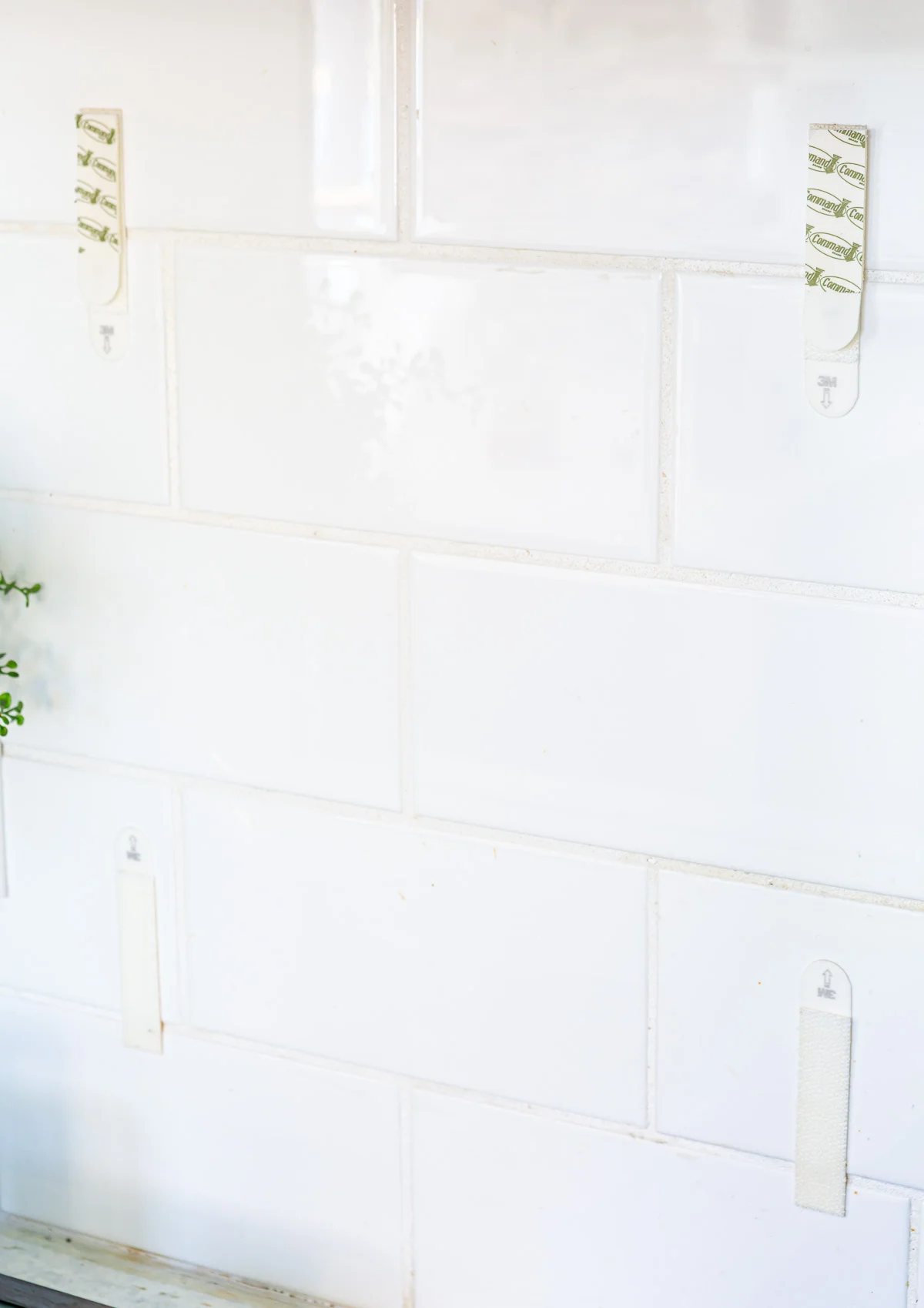 Command Brand picture hanging strips attached to tile backsplash in a kitchen ready to hang framed art.