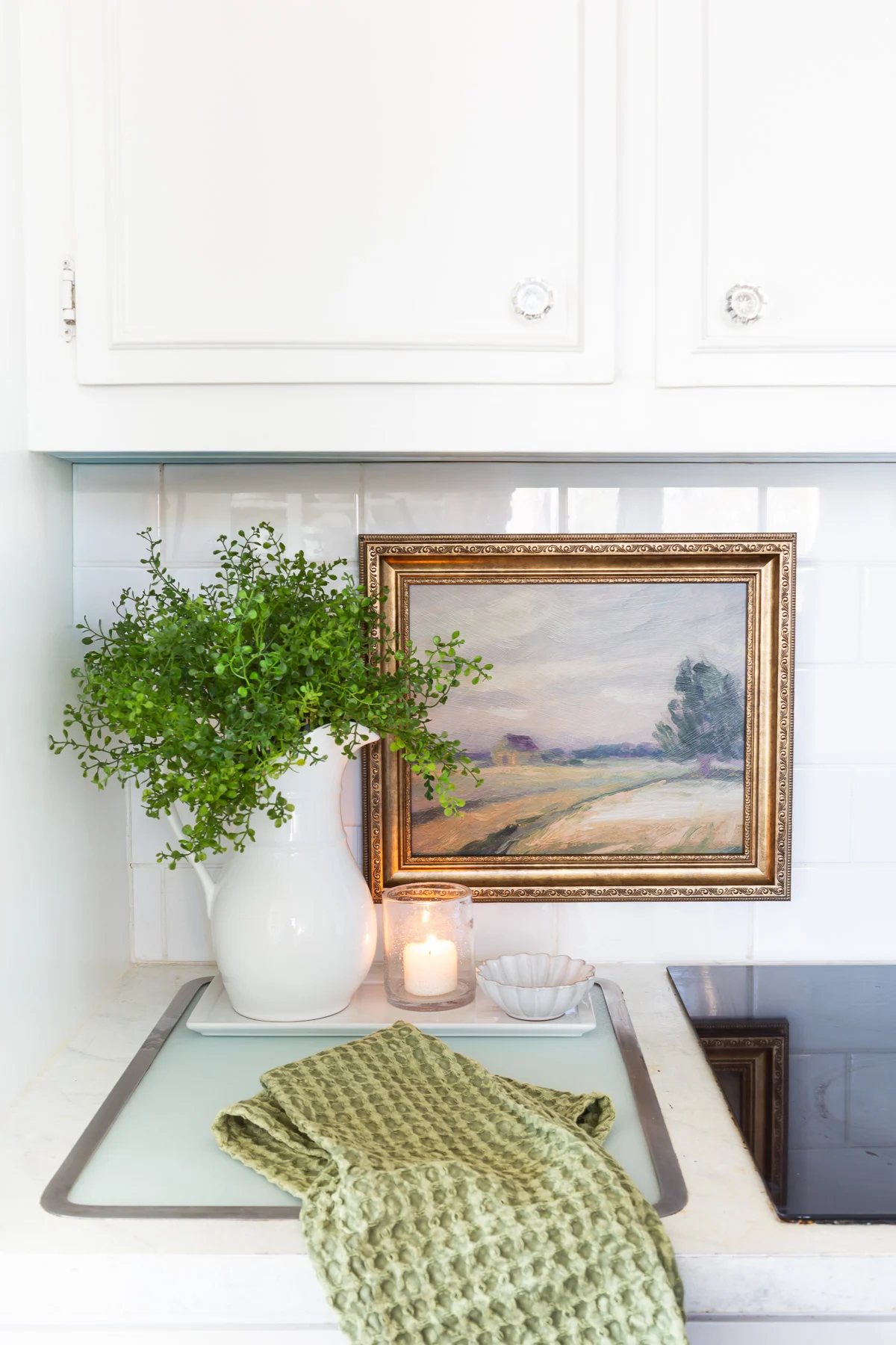 Looking at a kitchen counter where framed art is hung on the tile backsplash.