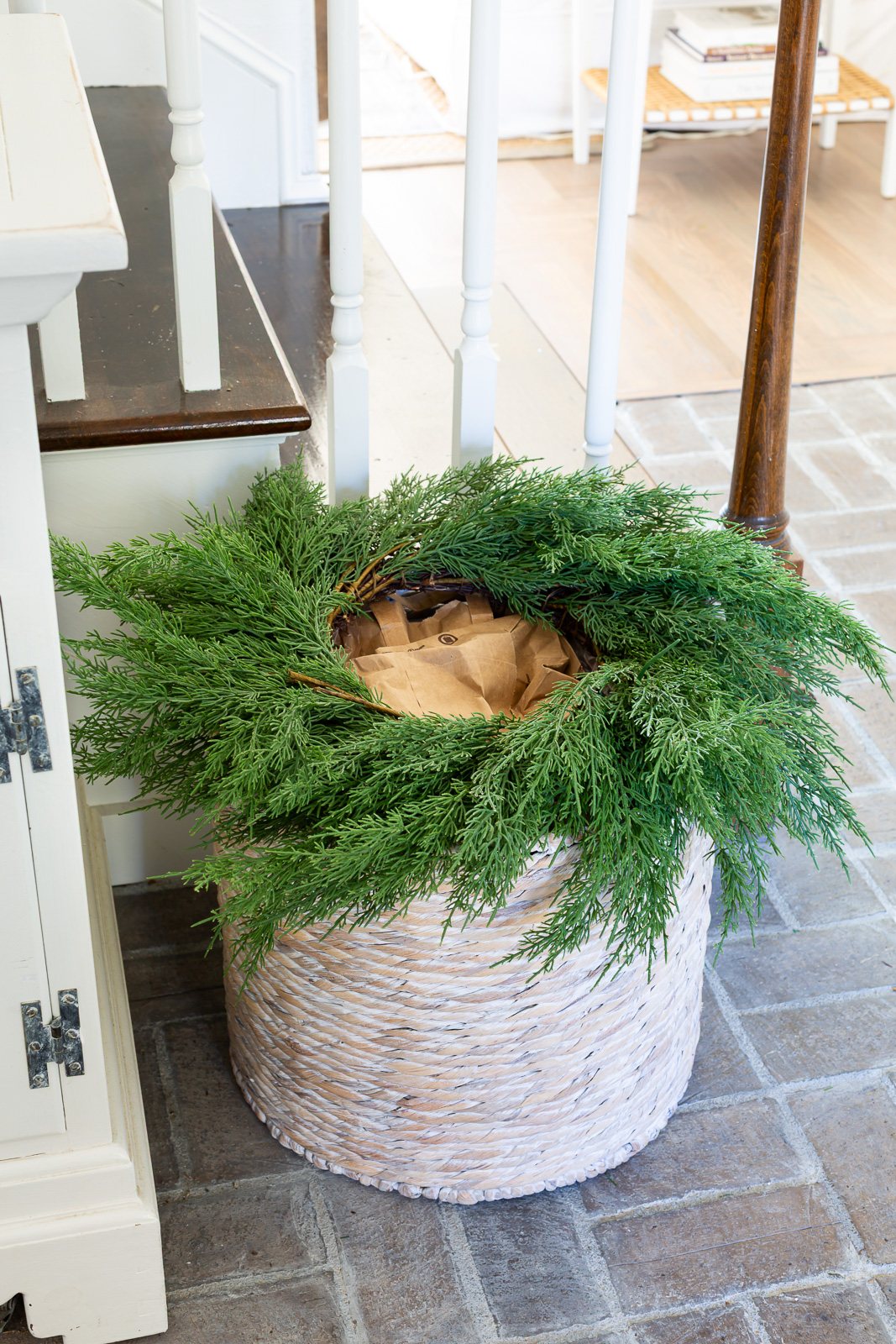 a wreath placed on top of a large floor basket in a foyer.