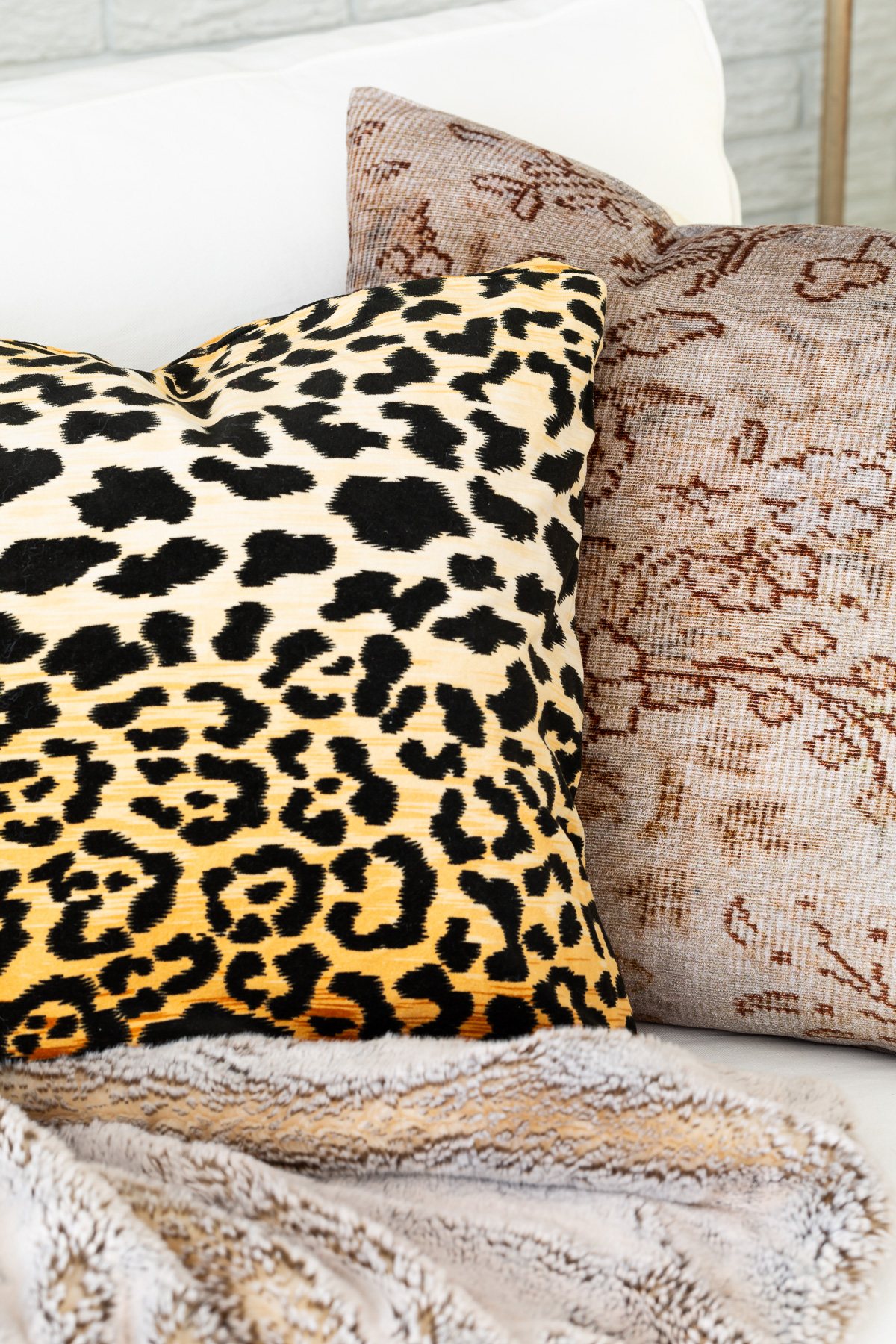 Leopard fabric and woven pillow covers on a sofa in a living room decorated for fall.