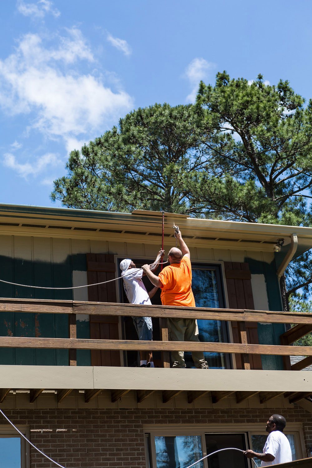 3 Painter's using a spray gun to paint the exterior of a home