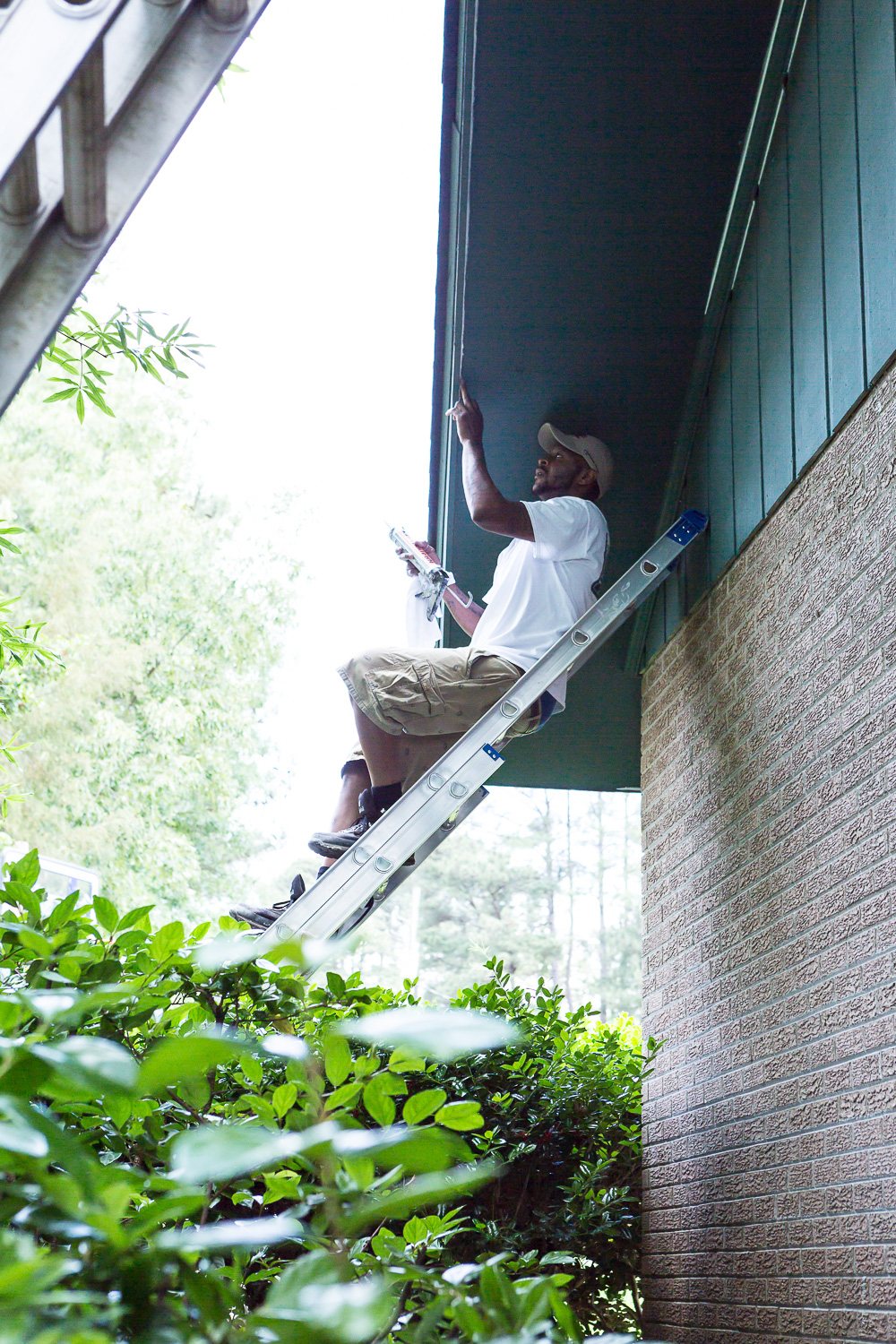 ladder propped up against house using a ladder leveling tool.
