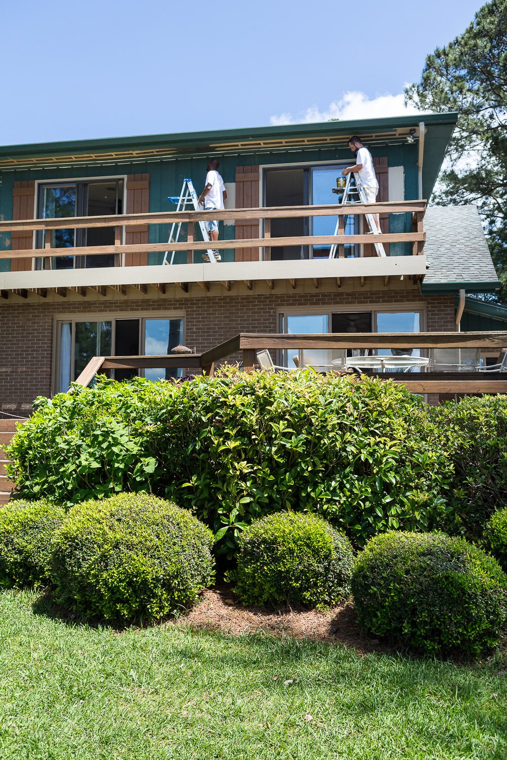 Two painters painting the outside of a houwe