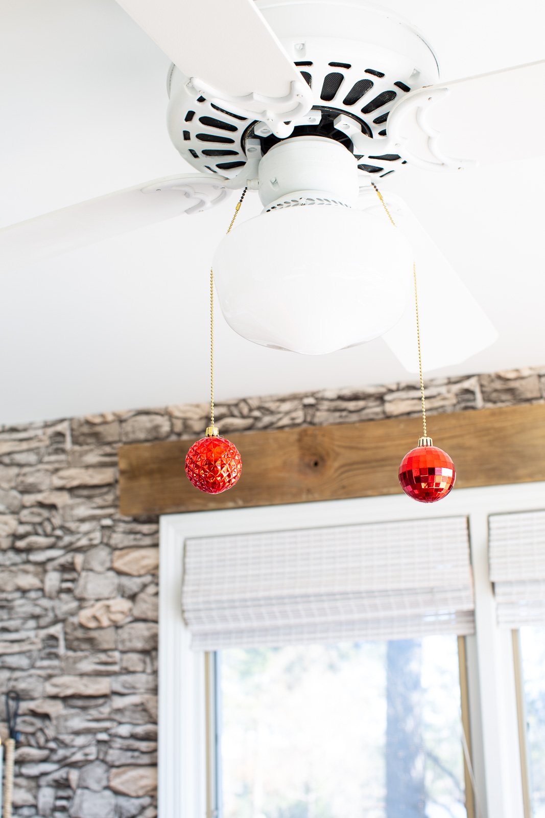 Christmas Decorating DIY in kitchen - adding shiny Christmas ornaments to the ends of the ceiling fixture pull chains.