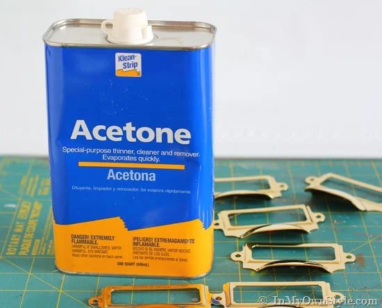 Bottle of acetone to remove lacquer from metal and brass pulls on work table