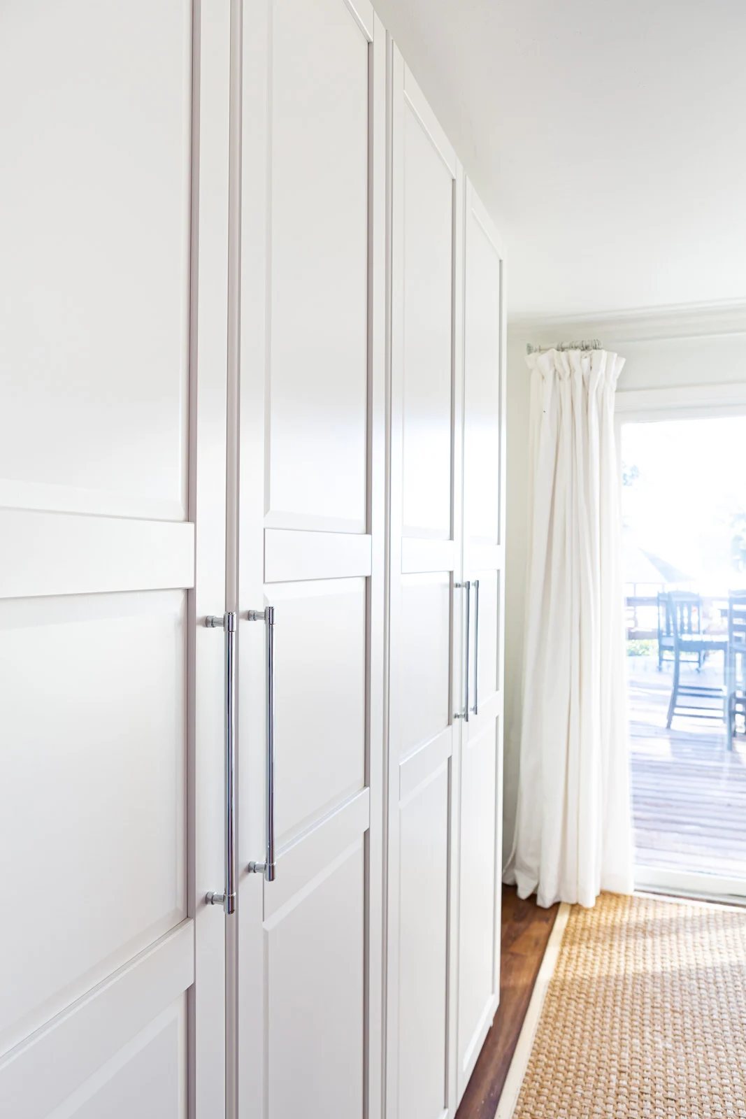 View of two side-by-side IKEA PAX storage units in white in a multi-purpose room in a home.