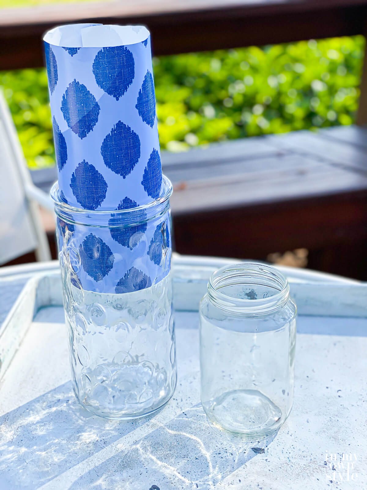 Tall glass vase being decorated with giftwrap on the inside . Then place a smaller glass vase or jar inside to hold water and fresh flowers.