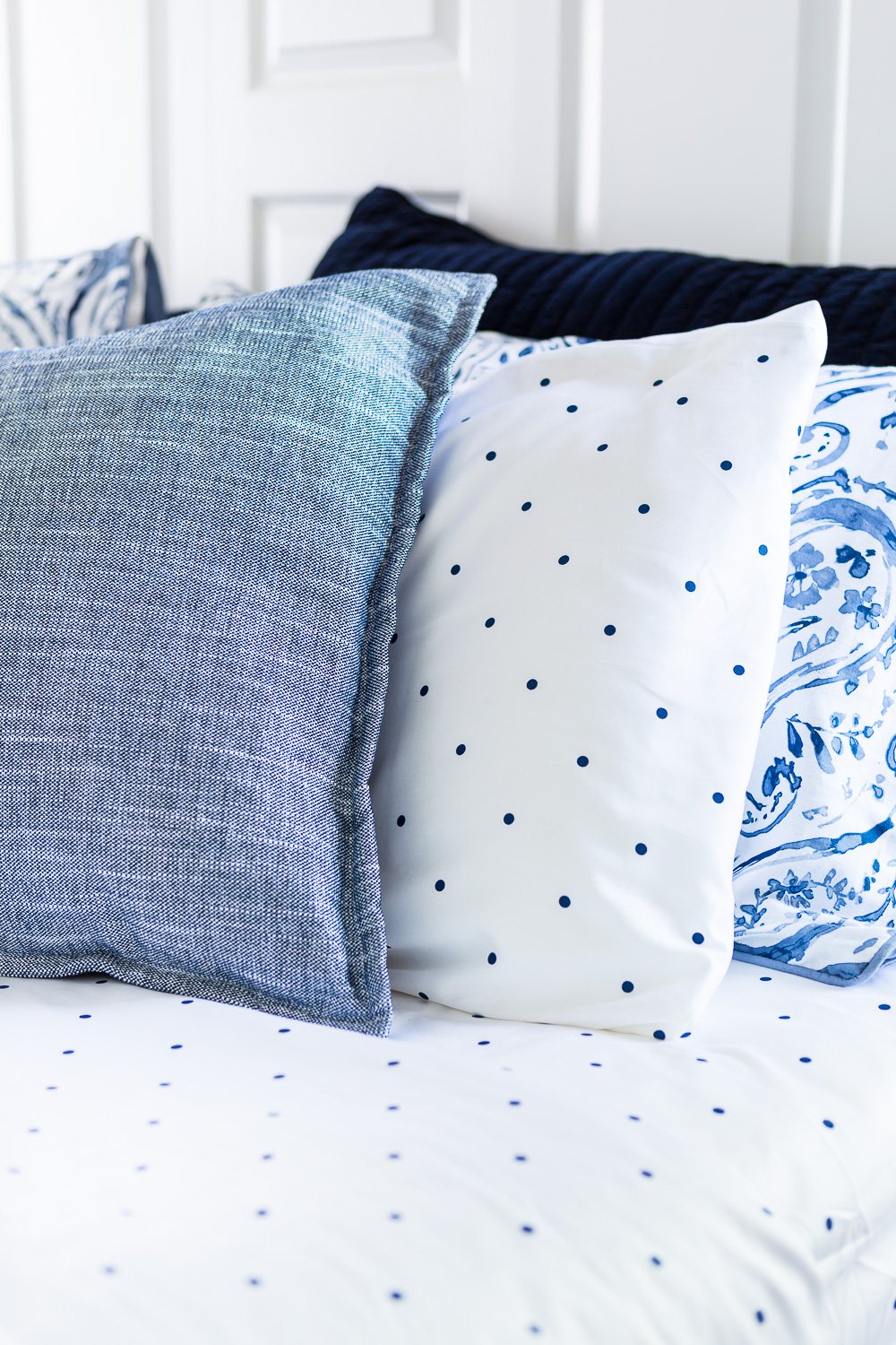 3 Blue and white bed pillows on a bed