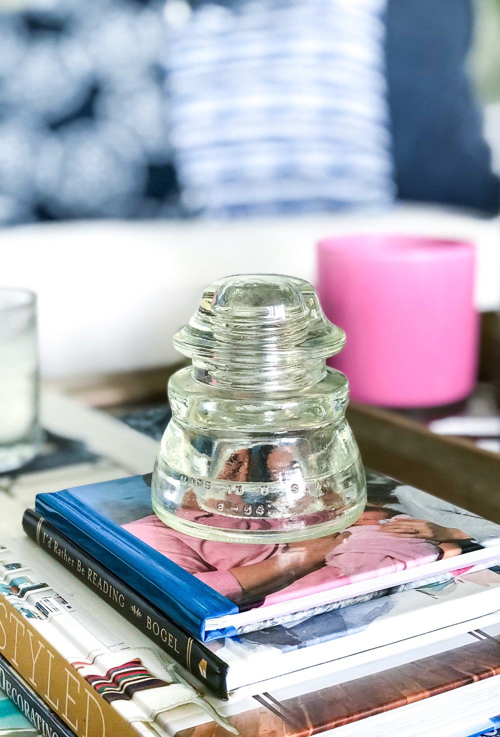Vintage find a telephone wire glass insulator becomes meaningful home decor when placed on a stack of coffee table books.