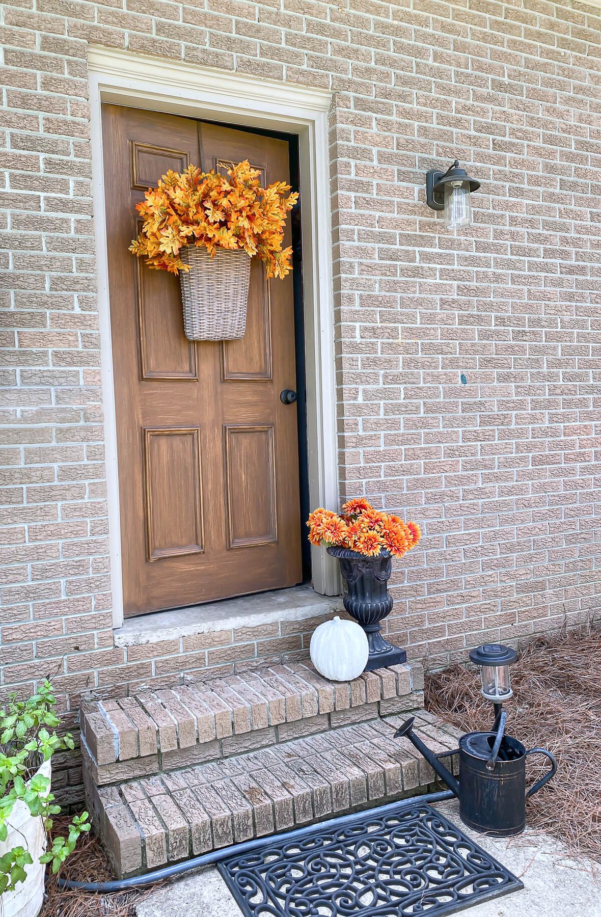 Orange hued fall leaves in abundance in a hanging basket on an exterior door.