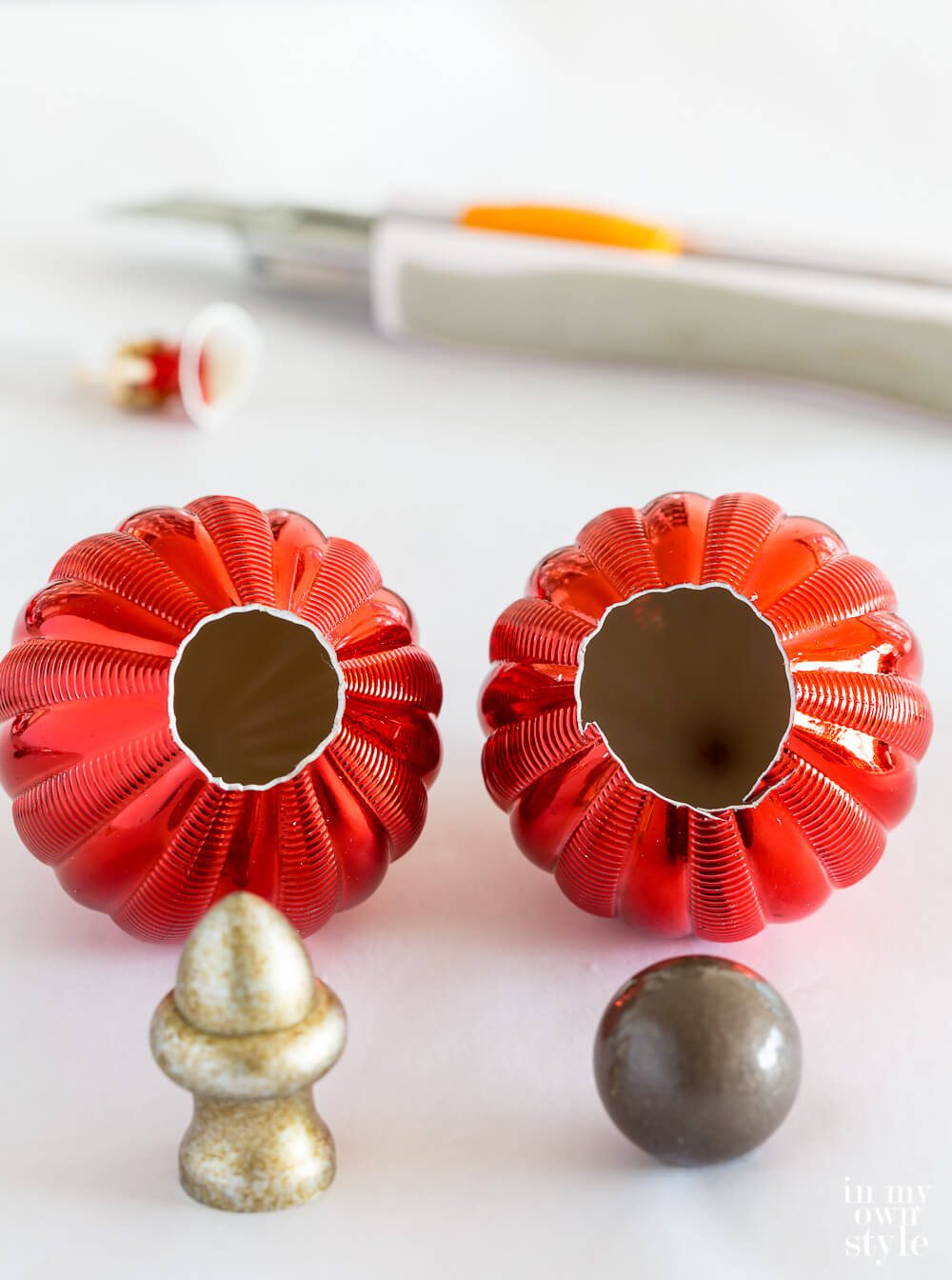 Two cut shatterproof ornaments and two lamp finials on a worktable.