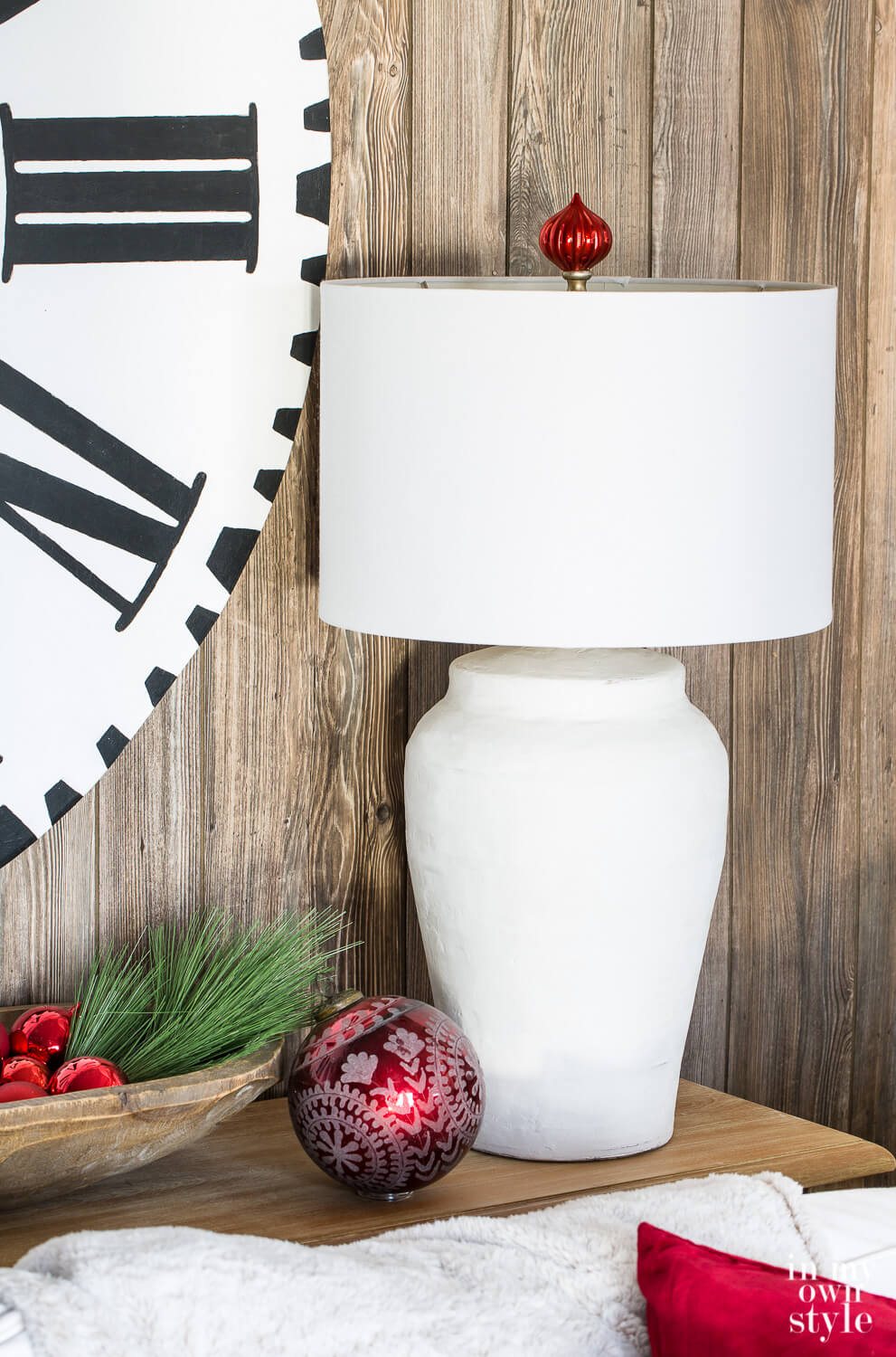Holiday lamp finial idea. Close up of white table lamp with red Christmas ball ornament made into a finial above the lamp shade.