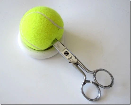 tennis ball being cut with scissors