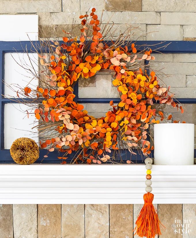 Fall wreath on mantel with a blue painted repurposed old wood window frame behind it.