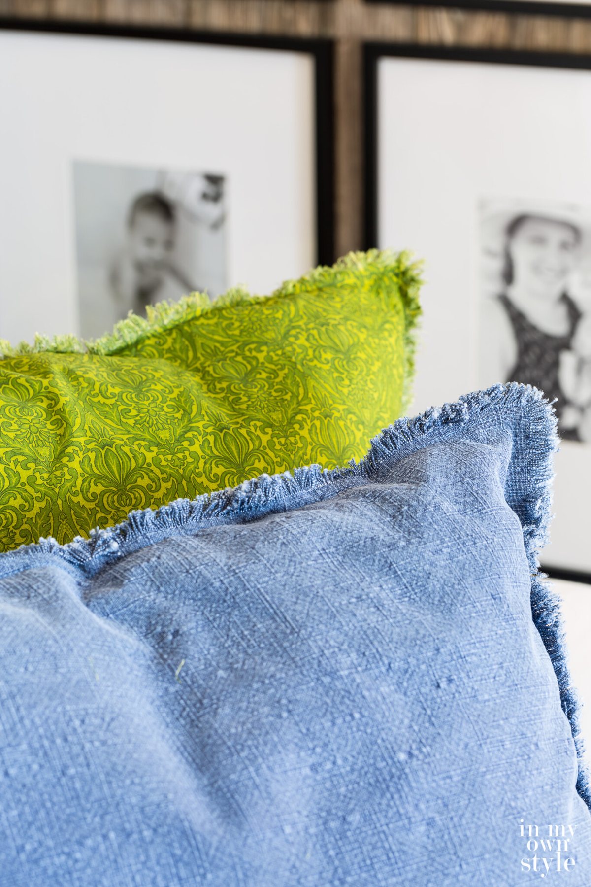 Two large fringe edged pillows on a sofa. One green and one blue.