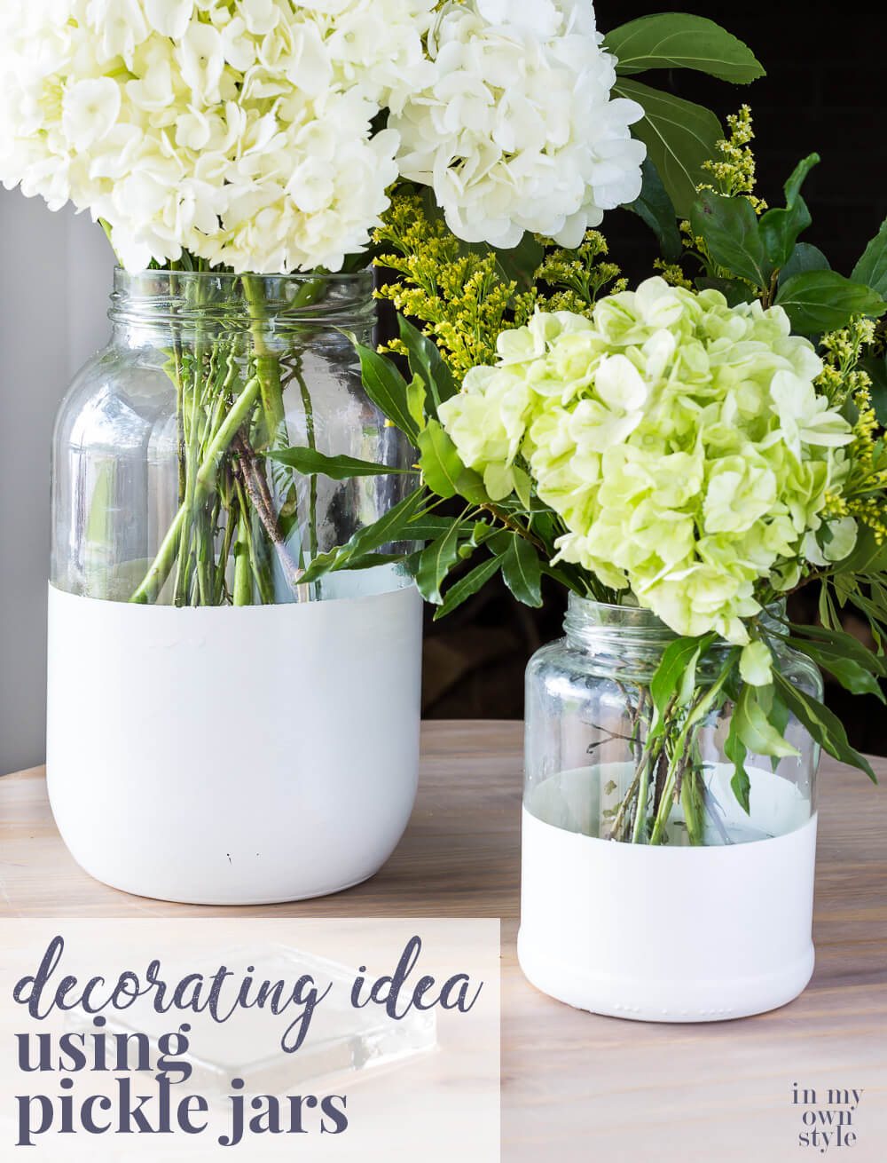 Two glass pickle jars transformed into chic vases by dipping in white paint. Text overlay says Decorating Idea using pickle jars.