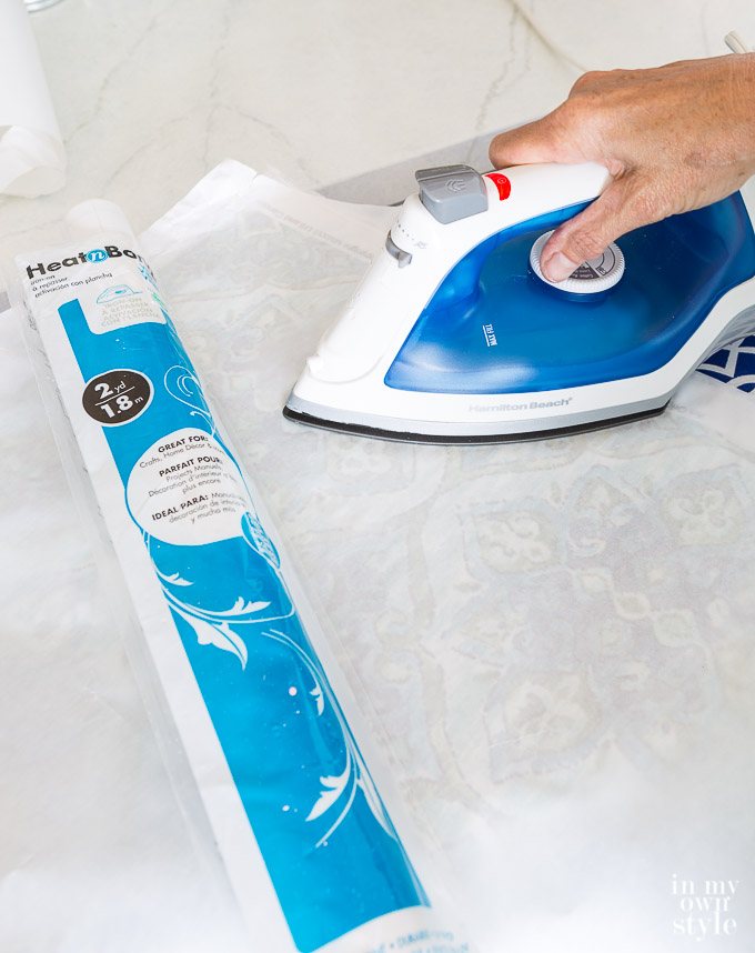 Using an iron to press heat n bond vinyl onto fabric.