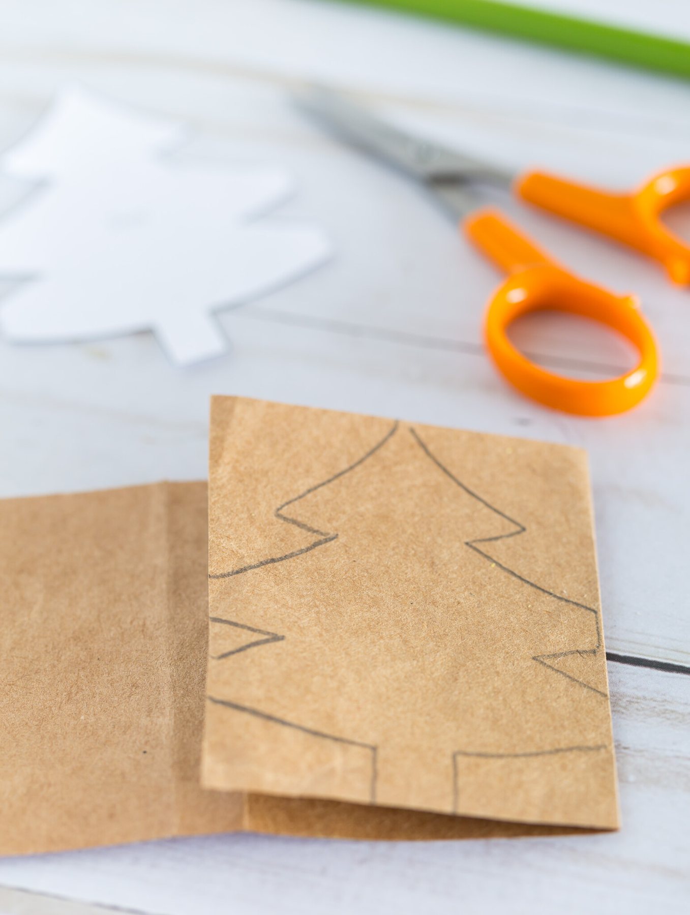 How to start folding a template of a Christmas tree pattern on to a strip of paper.