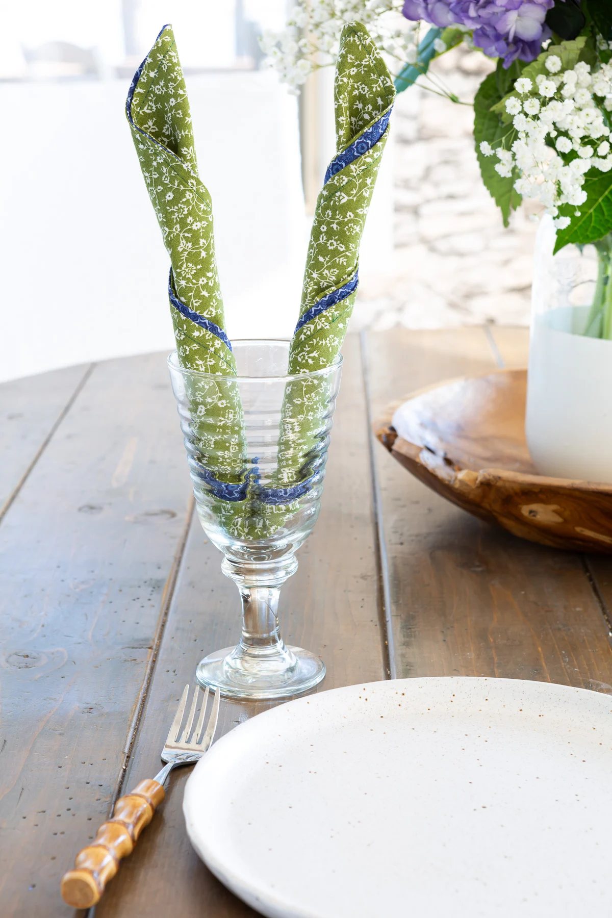 Way to fold a napkin for impact on a dining table. Rolled into bunny ears to place in a stemmed drinking glass.