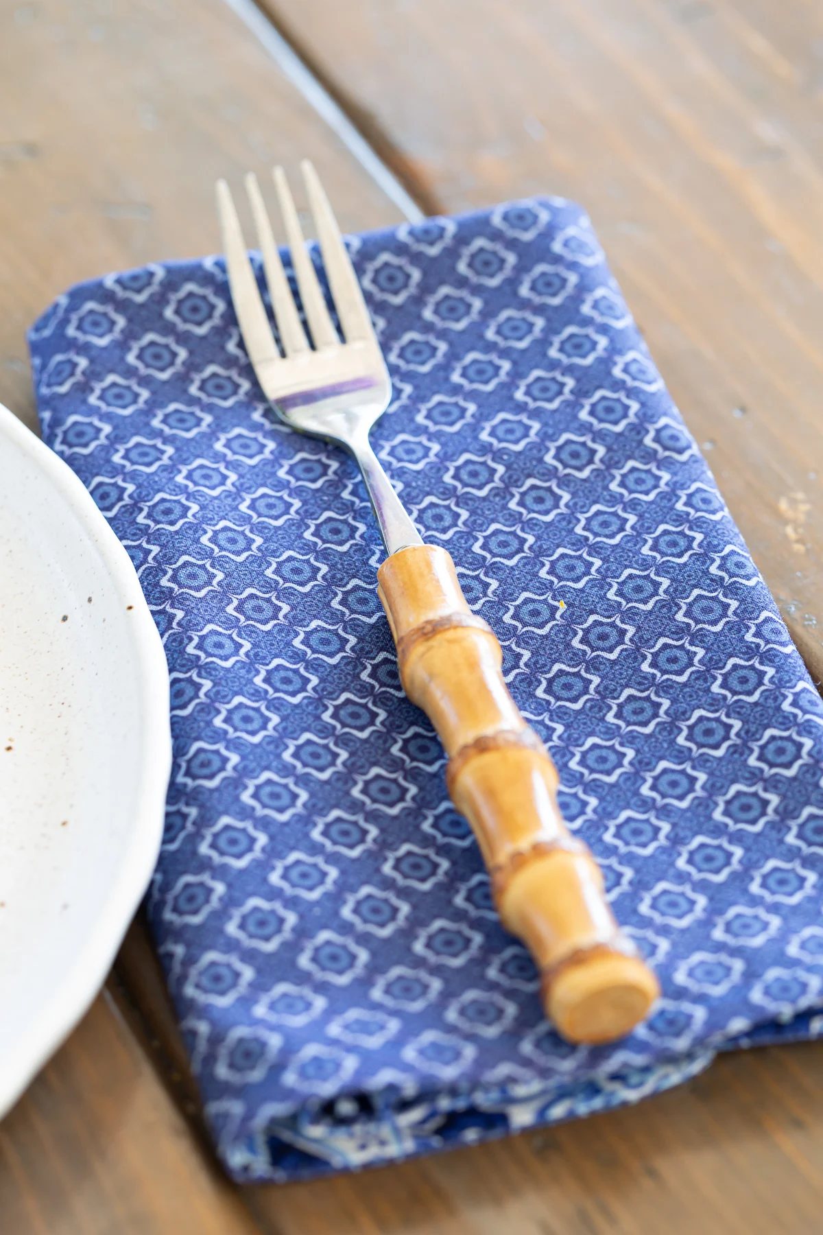 blue/white pattern fabric made into a luncheon sized napkin. Fork on top of napkin.