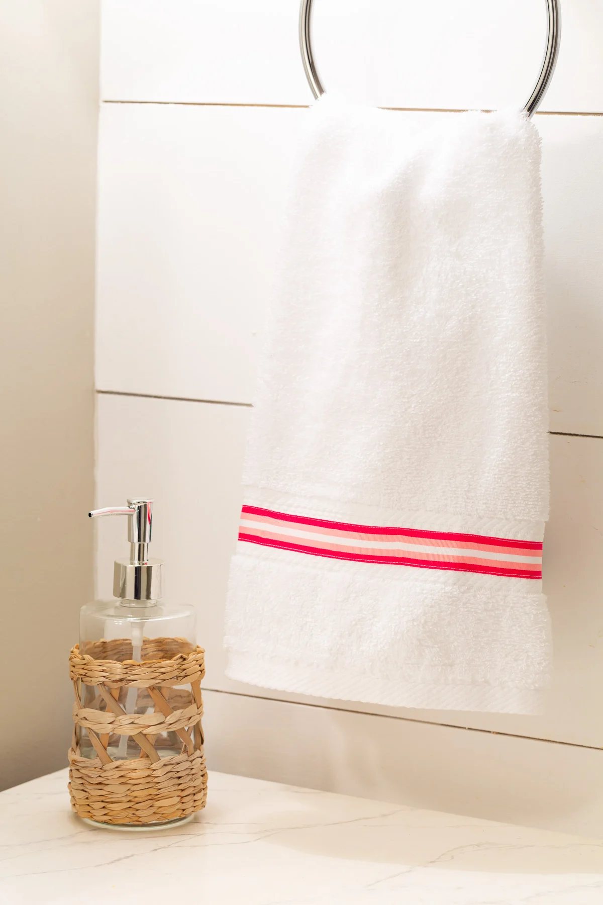 pink and white stripe ribbon sewn onto a bathroom hand towel.