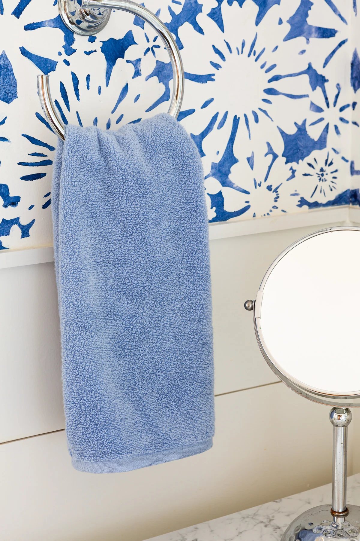plain blue bath towel hanging on a towel ring.