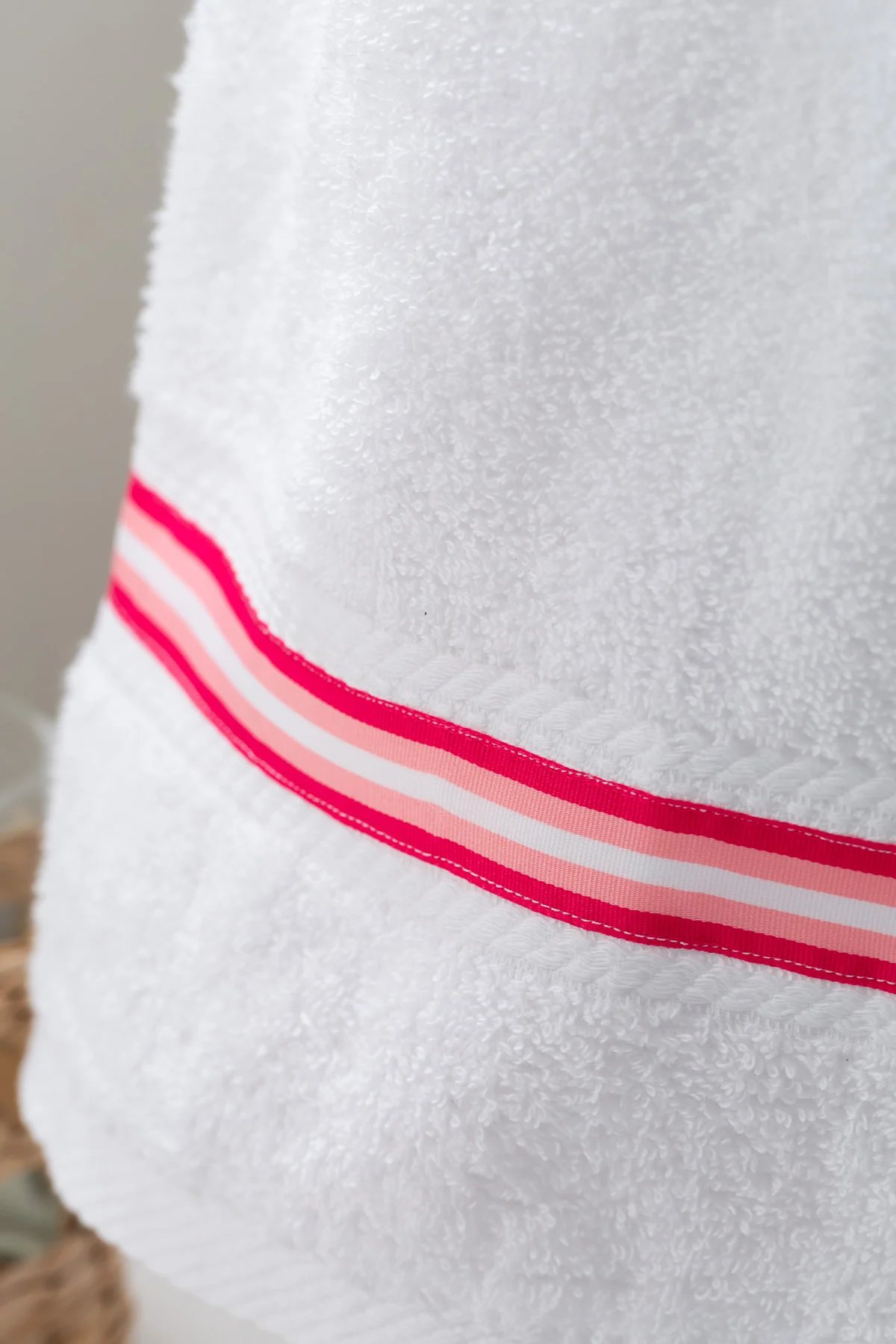 pink and white stripe ribbon sewn onto a bathroom hand towel.