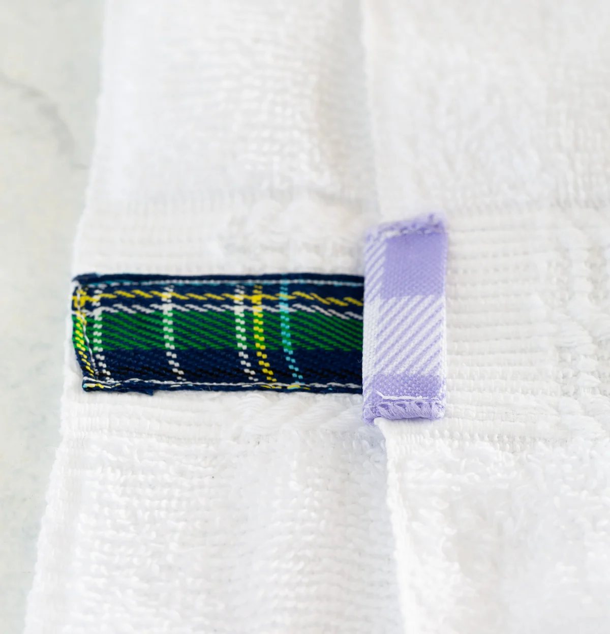 showing 2 ways to how to attach ribbon to a bathroom towel.