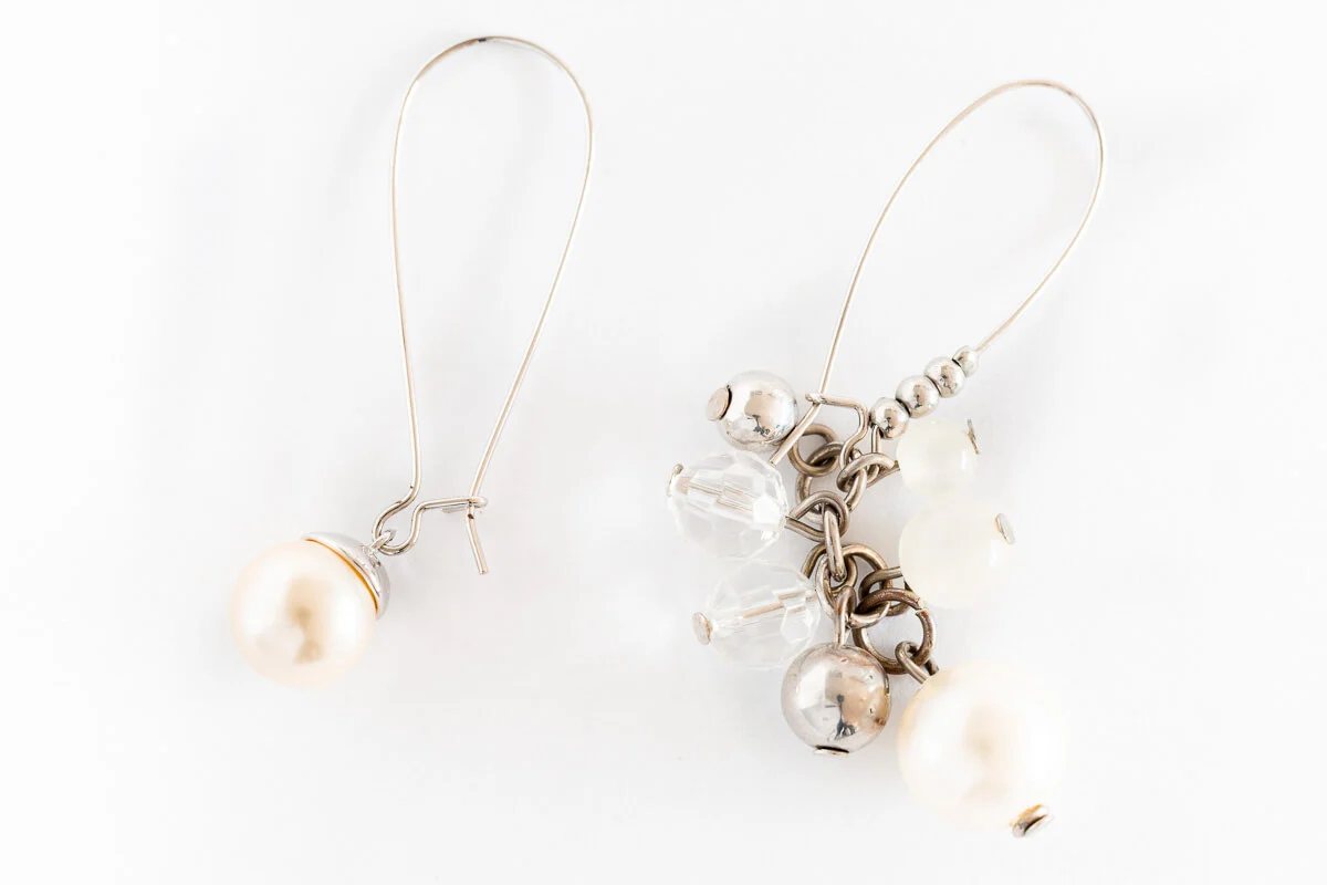 a pair of pearl dangle earrings -on with only one bead and the other a cluster of pearl, silver and crystal beads.