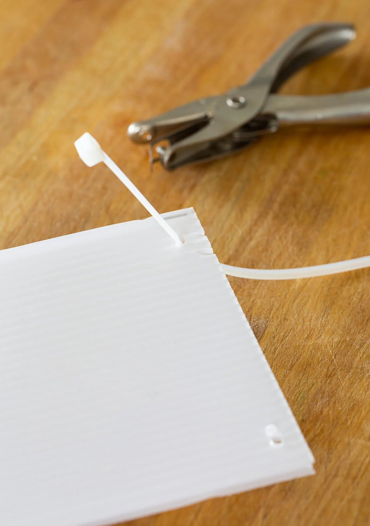 How to attach a zip tie to plastic corrugated sheet to make freezer drawer dividers.