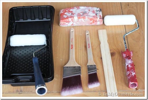 Furniture-Painting-tools tray, rollers;; brushes and stirring stick on table.